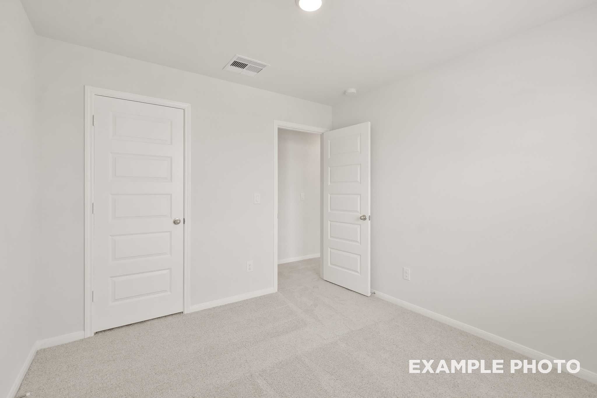 Spacious bedroom with white doors and carpet in The Brazos by Davidson Homes, Beasley TX new construction home
