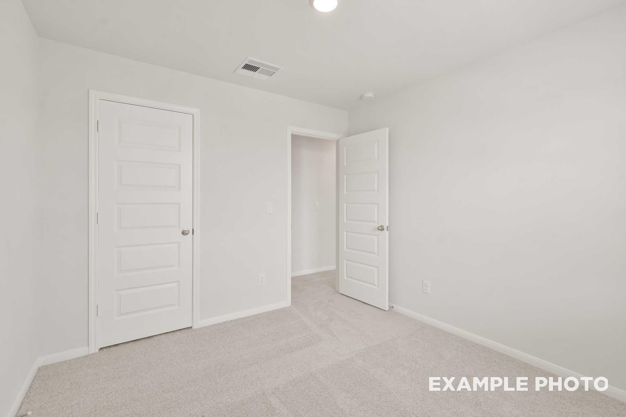 Spacious bedroom with white doors and carpet in The Brazos by Davidson Homes, Beasley TX new construction home