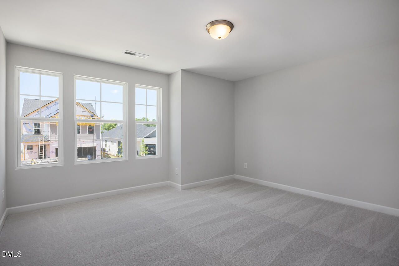 Bright bedroom with neutral carpet and large windows in The Adalynn B floor plan at Gregory Village, Lillington, NC.