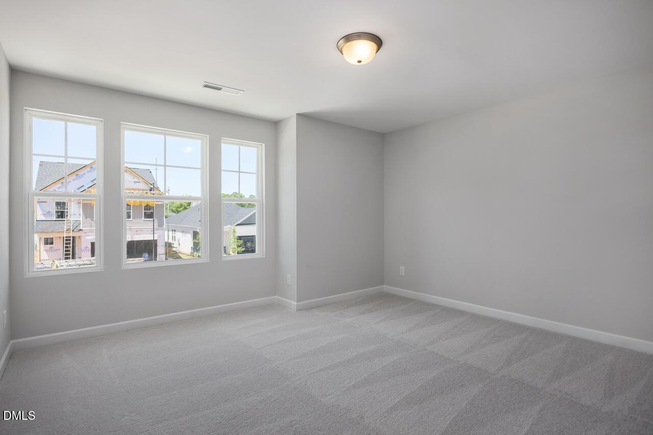Bright bedroom with neutral carpet and large windows in The Adalynn B floor plan at Gregory Village, Lillington, NC.