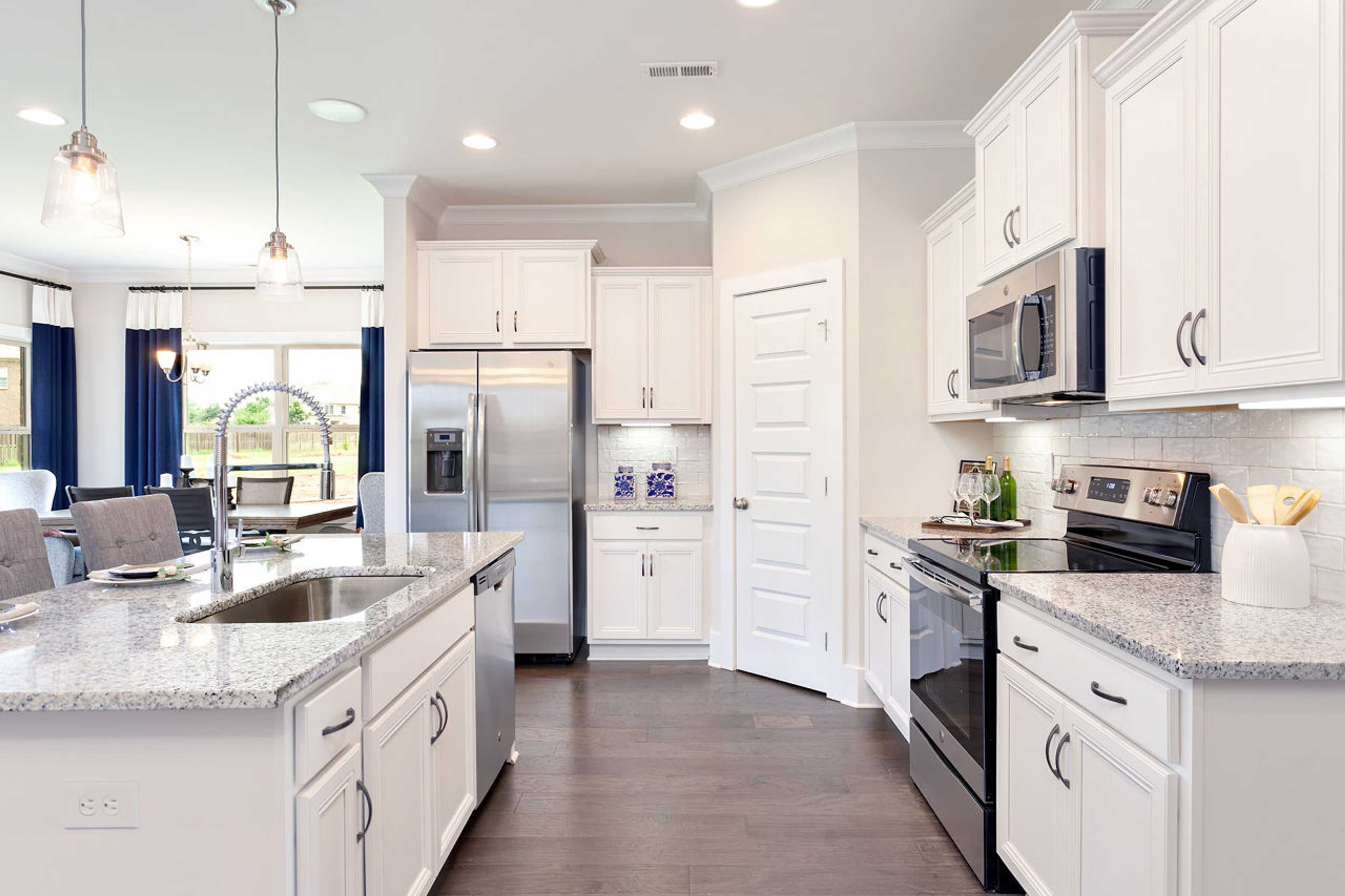 Spacious modern kitchen at Williams Pointe in Huntsville Alabama with white cabinets granite island and stainless steel appliances