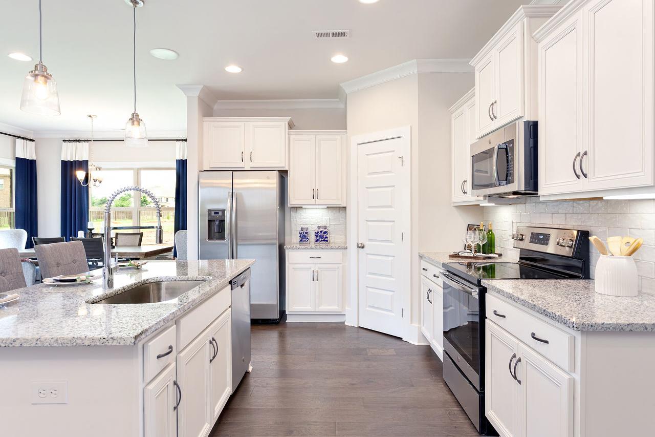 Spacious modern kitchen at Williams Pointe in Huntsville Alabama with white cabinets granite island and stainless steel appliances