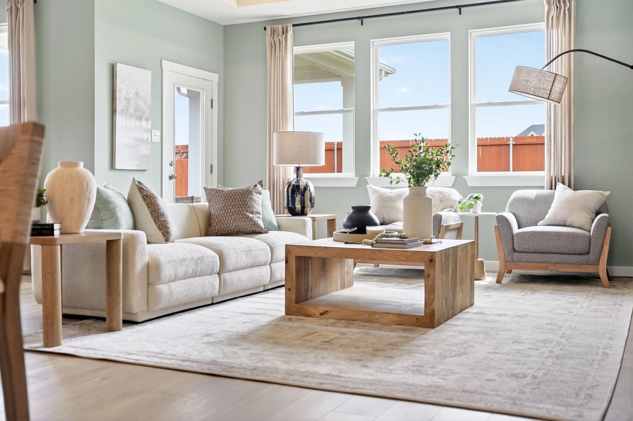 Bright, open-concept living room with modern decor in The Laurel M floor plan at Parks at Foster Crossing in Anna, Texas.