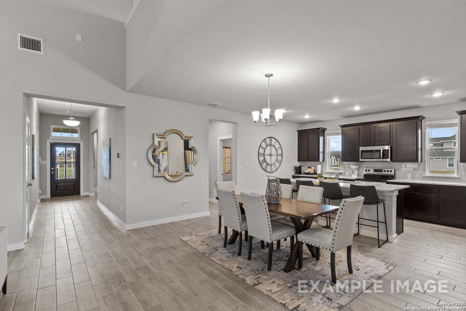 Open-concept dining area with large mirror, wooden table, and modern kitchen island in Davidson Homes The Collin A, Seguin TX