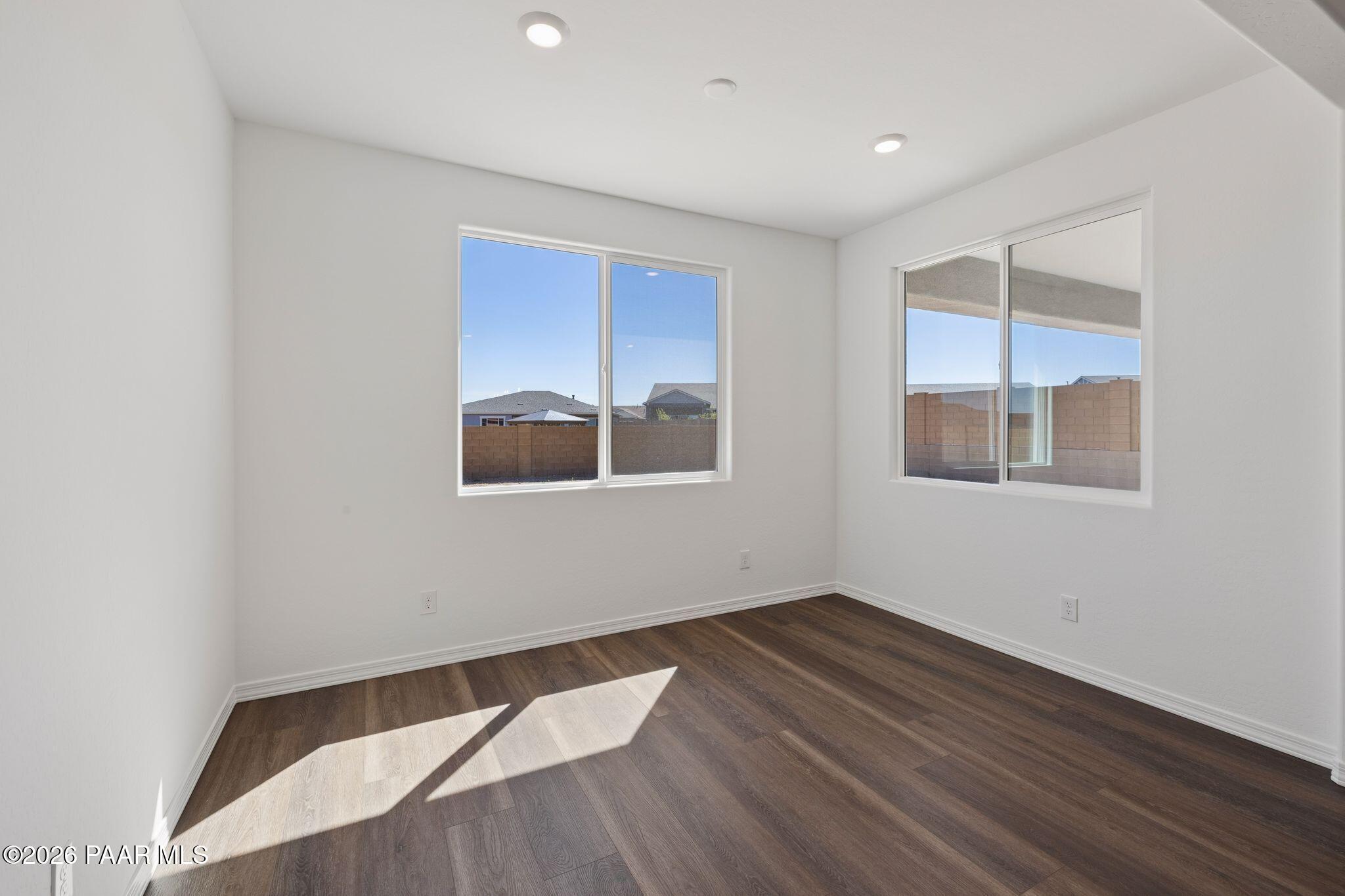 Bright secondary bedroom with large sunny windows, white walls, and hardwood floors in Davidson Homes The Monarch A, Prescott, AZ