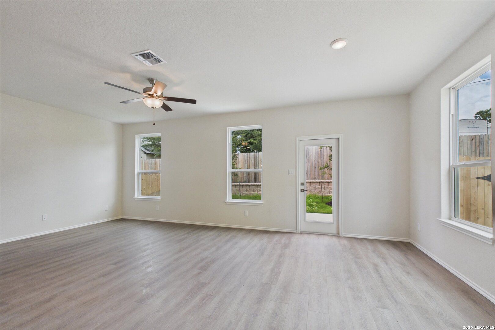 Bright, spacious living room with wood-look flooring and backyard access in The Charlotte B, Meadows at Oak Creek.