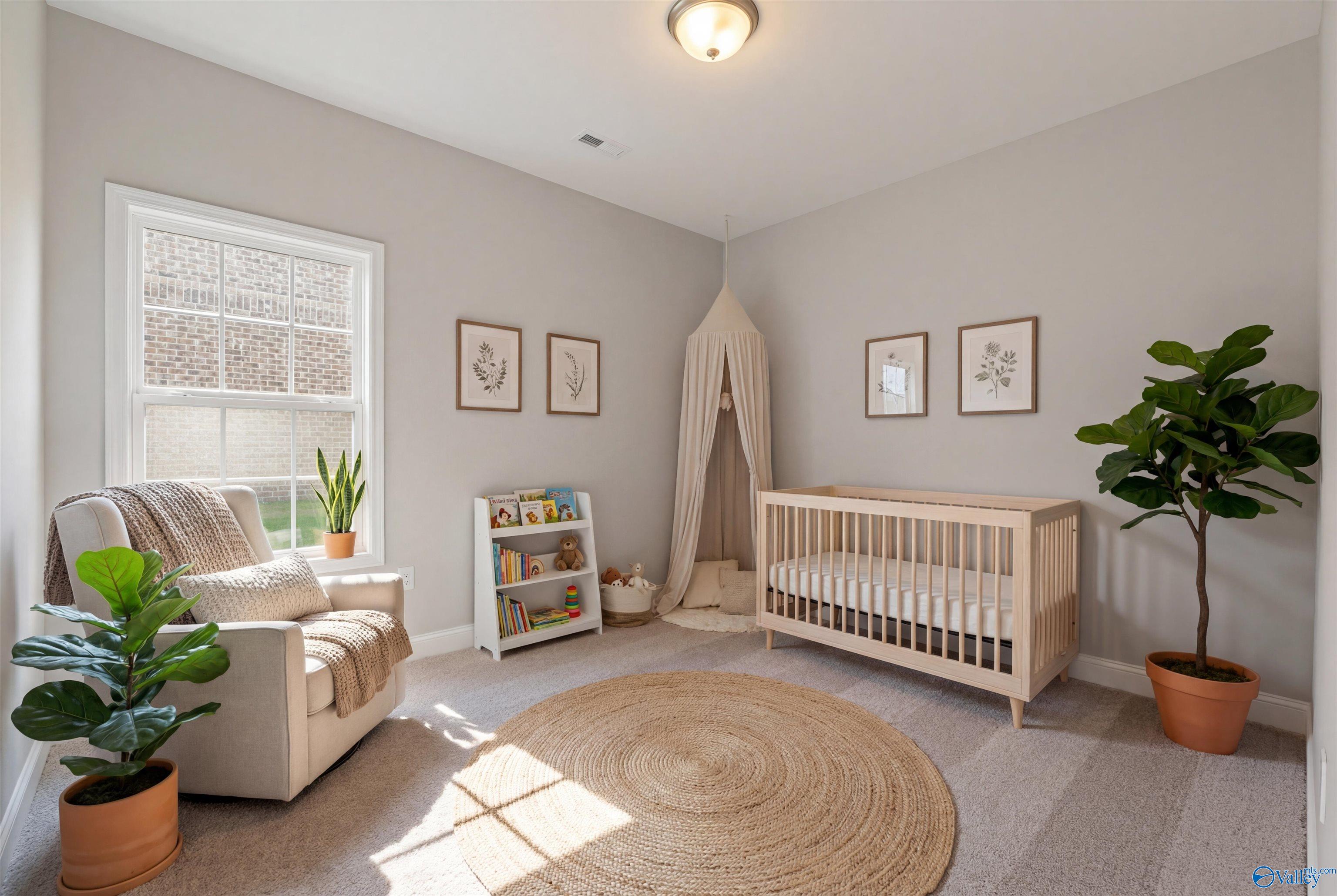 Cozy nursery with canopy crib, armchair, fiddle leaf fig plant, and bookshelves in Davidson Homes The Rockford with Bonus, Toney, Alabama