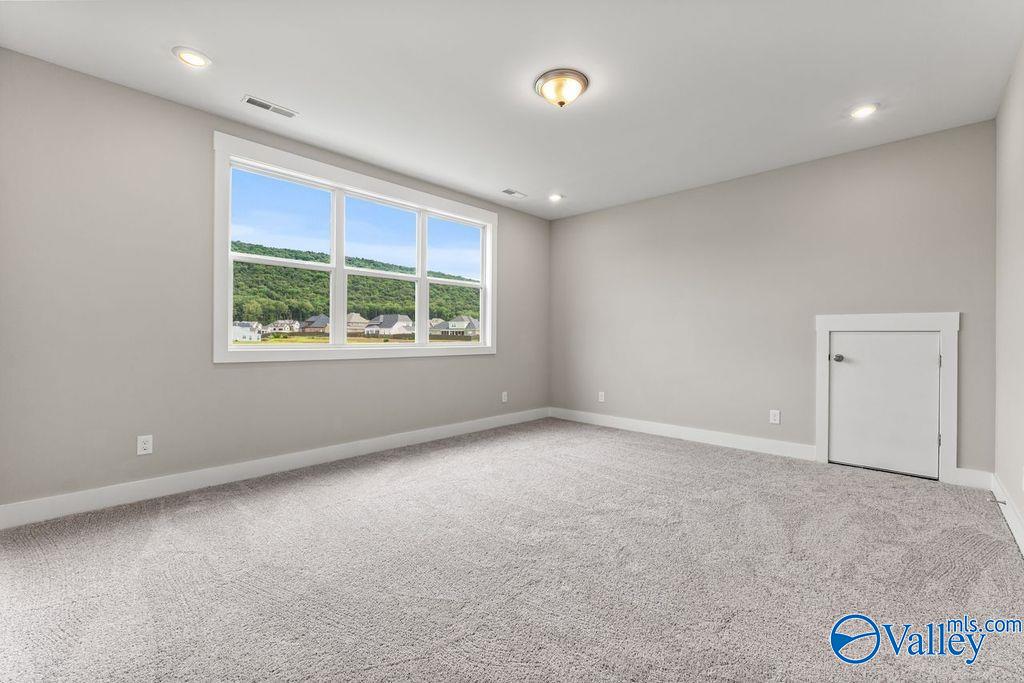 Bright empty bedroom with gray walls, carpet floor, large window to green view in Evermore Homes The Oxford, Owens Cross Roads, AL