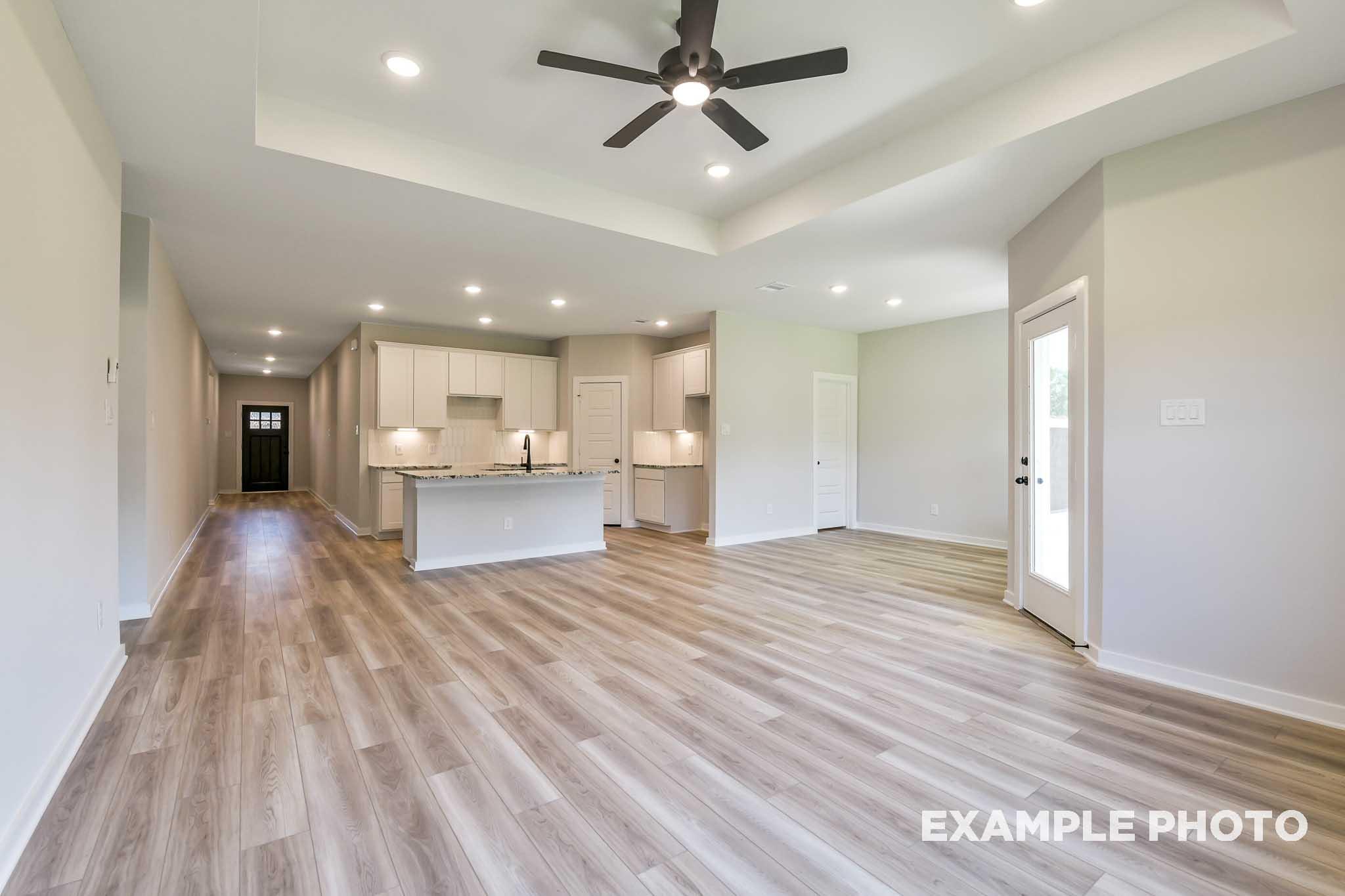 Spacious open-concept kitchen and living area in The Daphne G featuring white shaker cabinets, large island, ceiling fan, and luxury vinyl plank floors