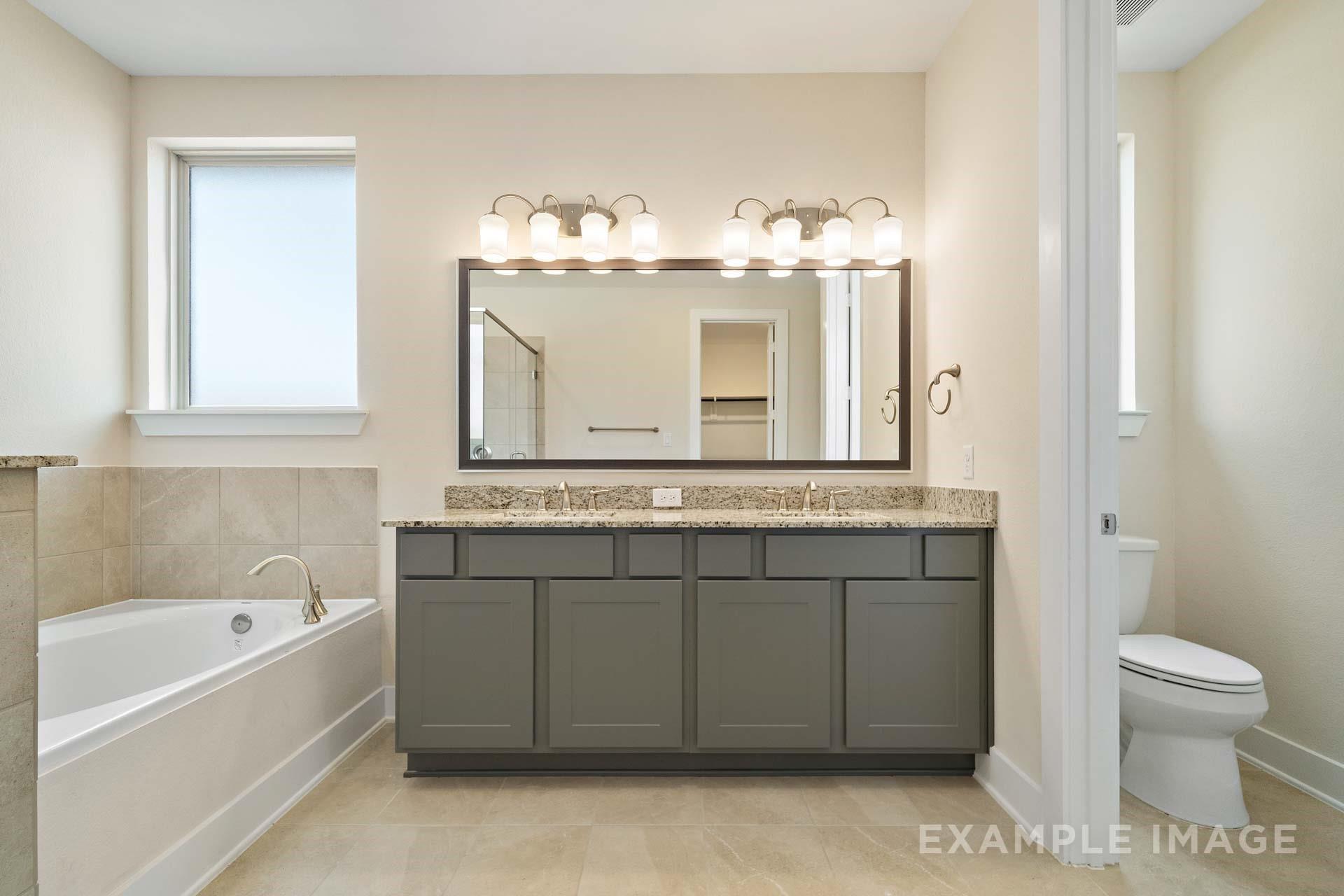 Double vanity bathroom with granite countertops, garden tub, and tile floors in Davidson Homes The Diana C, Lago Mar, Texas City