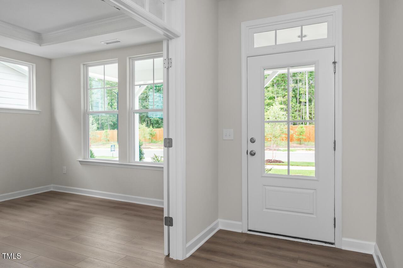Bright entry foyer with white glass-paneled door, large windows, hardwood floors in Davidson Homes The Aspen B, Wake Forest