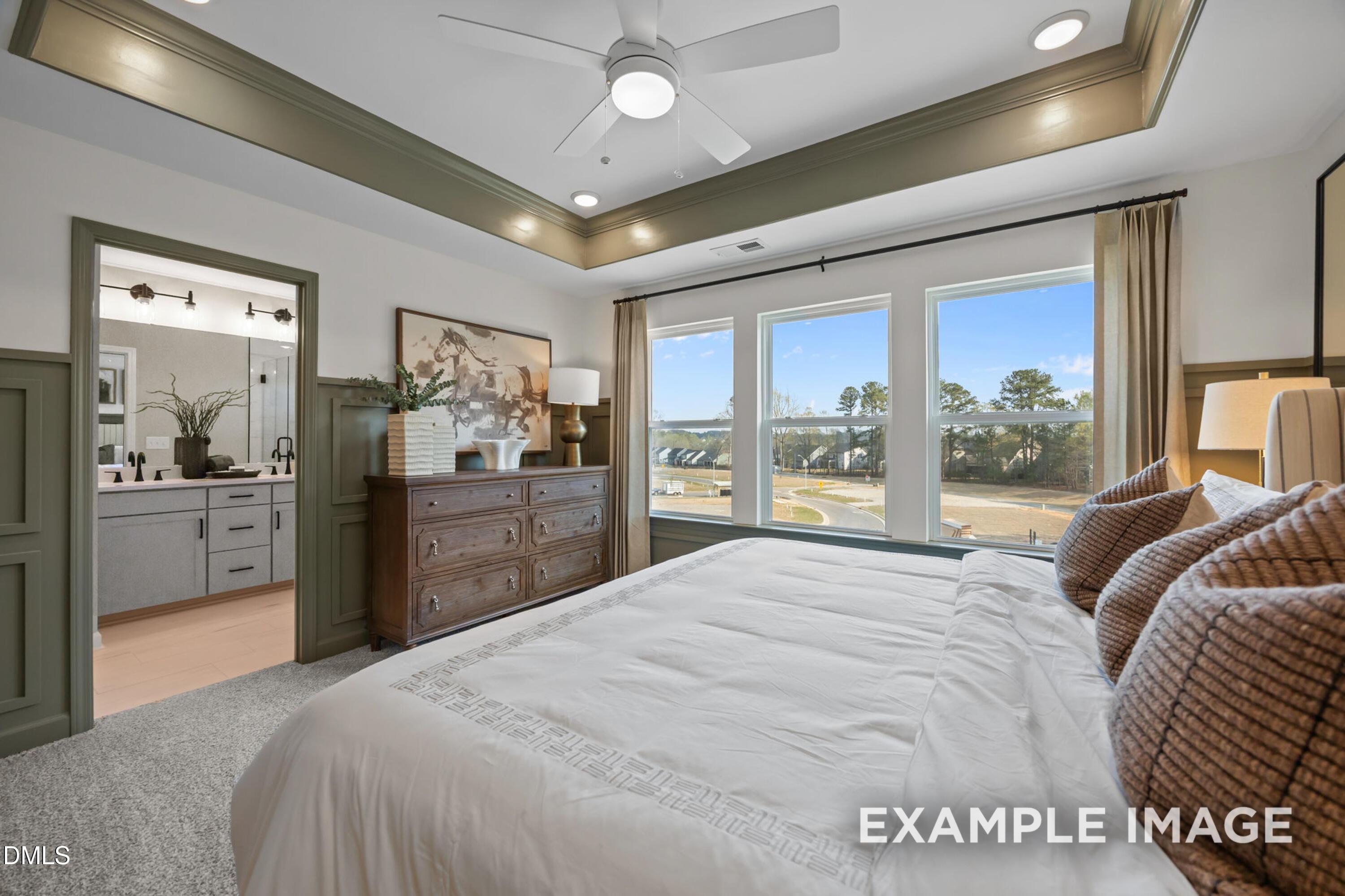 Luxurious master bedroom suite with en-suite bath, king bed, and scenic neighborhood view in Davidson Homes The Mitchell, Knightdale, NC