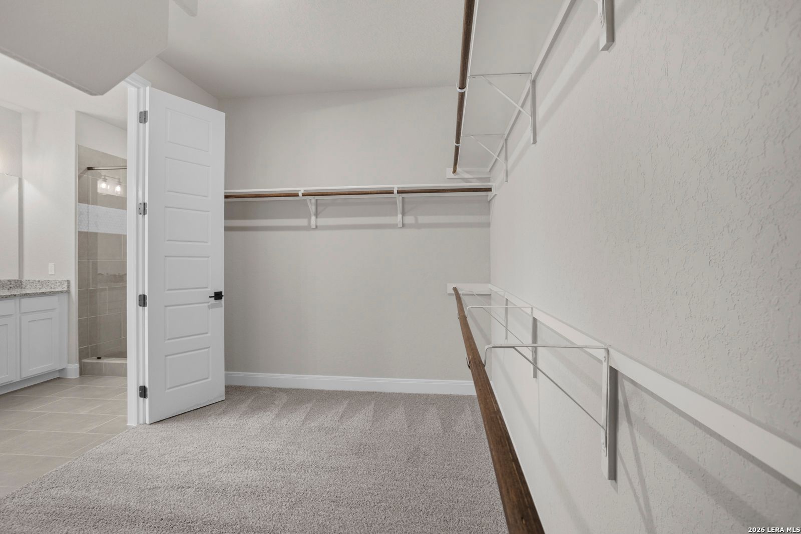 Walk-in closet with carpeted floors and shelving in The Jennings G floor plan by Davidson Homes in Ladera, San Antonio.