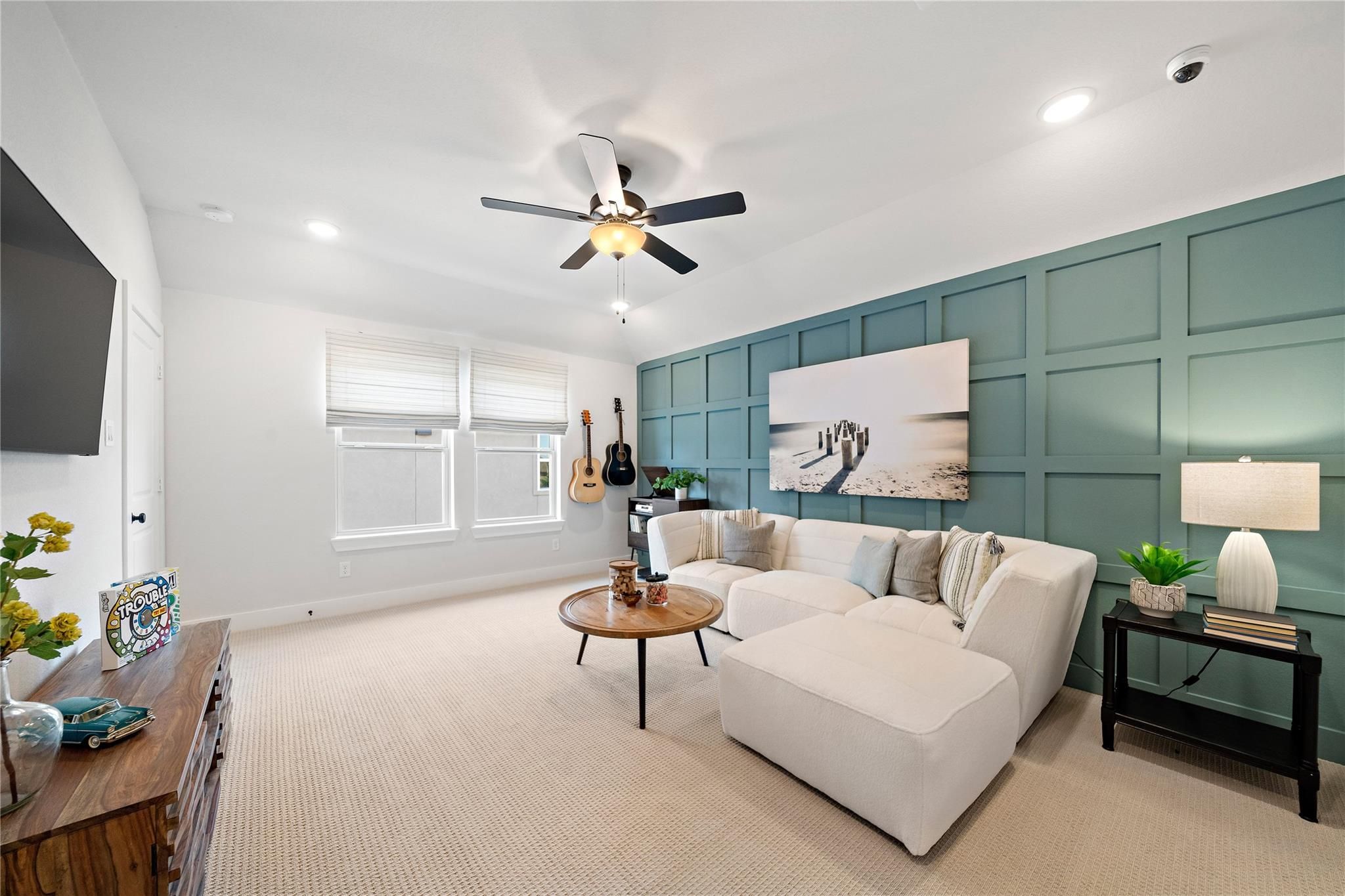 Cozy living room with white sectional sofa, teal accent wall, and ceiling fan in Davidson Homes The Edward A, Lago Mar, Texas City