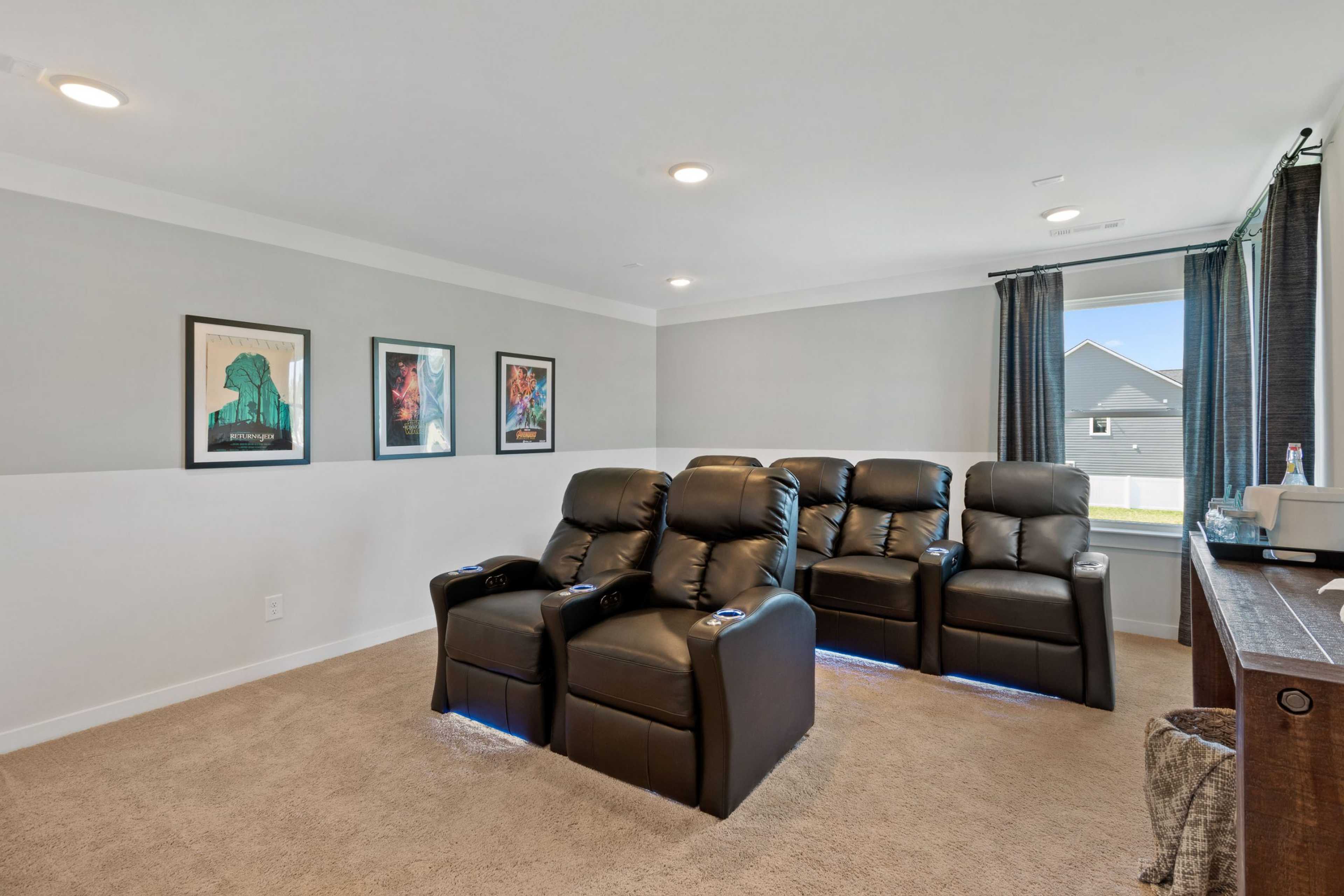 Home theater room at Rivers Edge in Murfreesboro TN with black leather recliners, movie posters, and carpeted floor