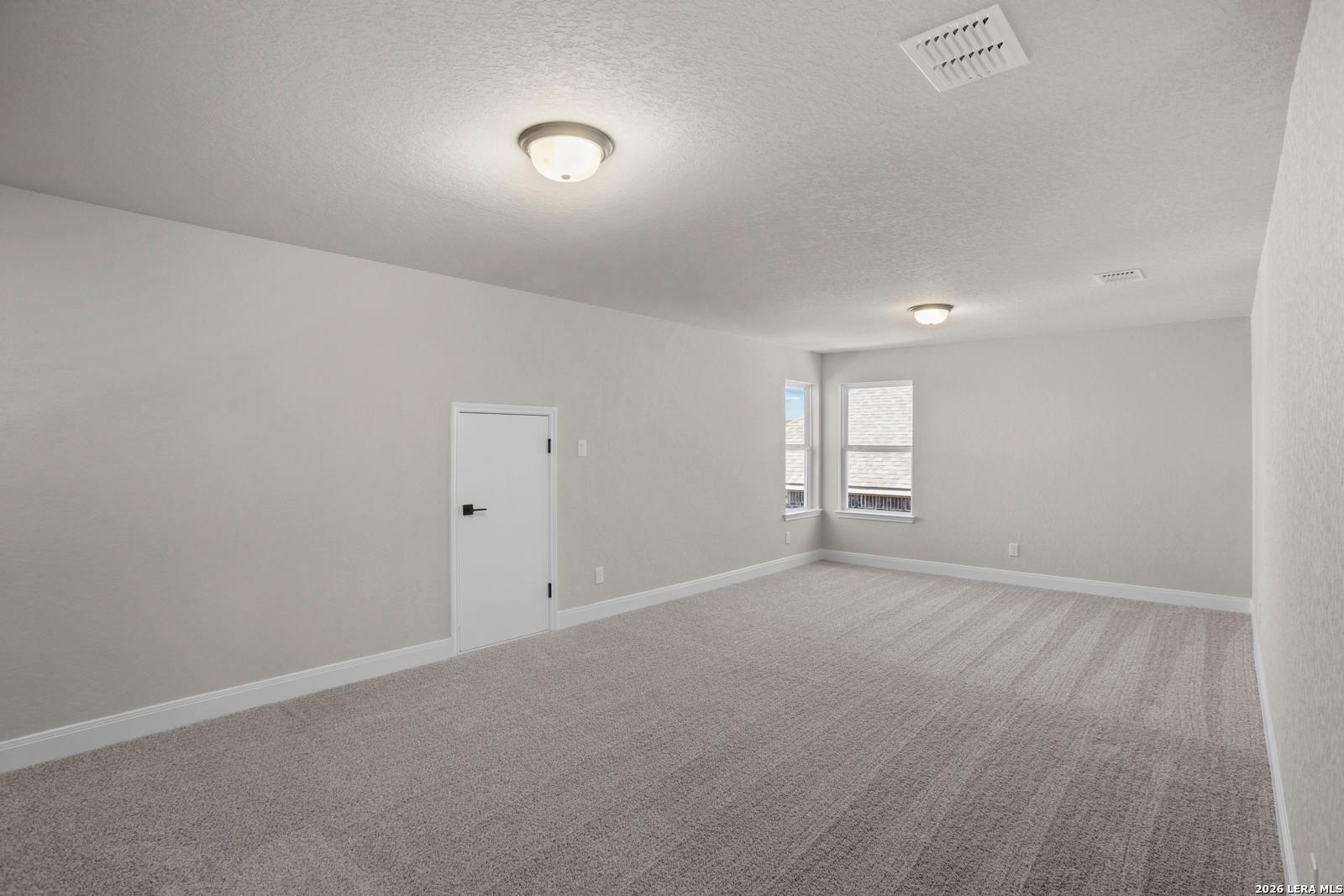 Spacious carpeted bedroom with neutral walls in The Jennings G floor plan by Davidson Homes in Ladera, San Antonio, Texas.