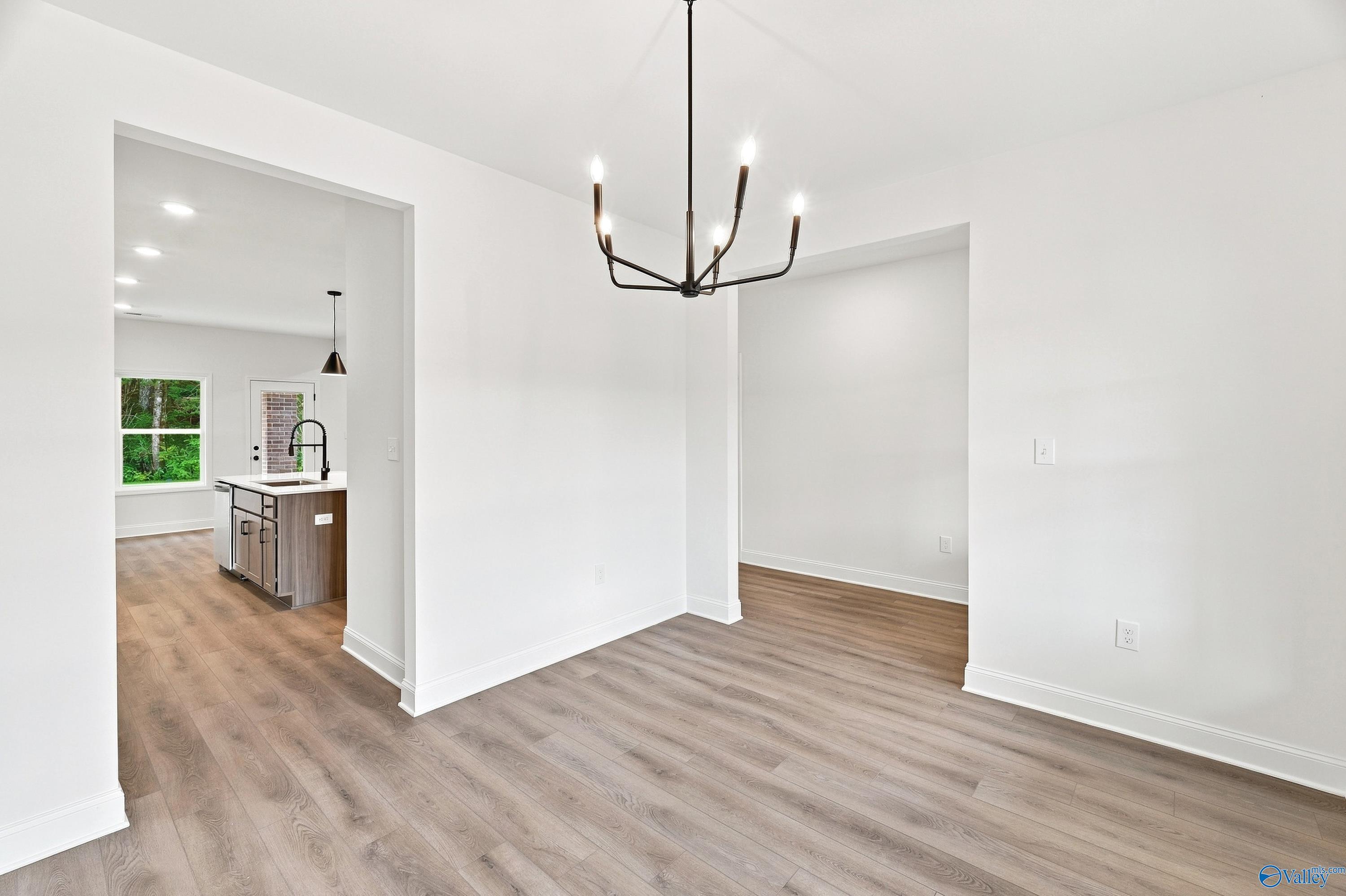 Bright dining area with modern chandelier and wood-look flooring in The Shelby B floor plan, Jaguar Hills, Huntsville, AL.