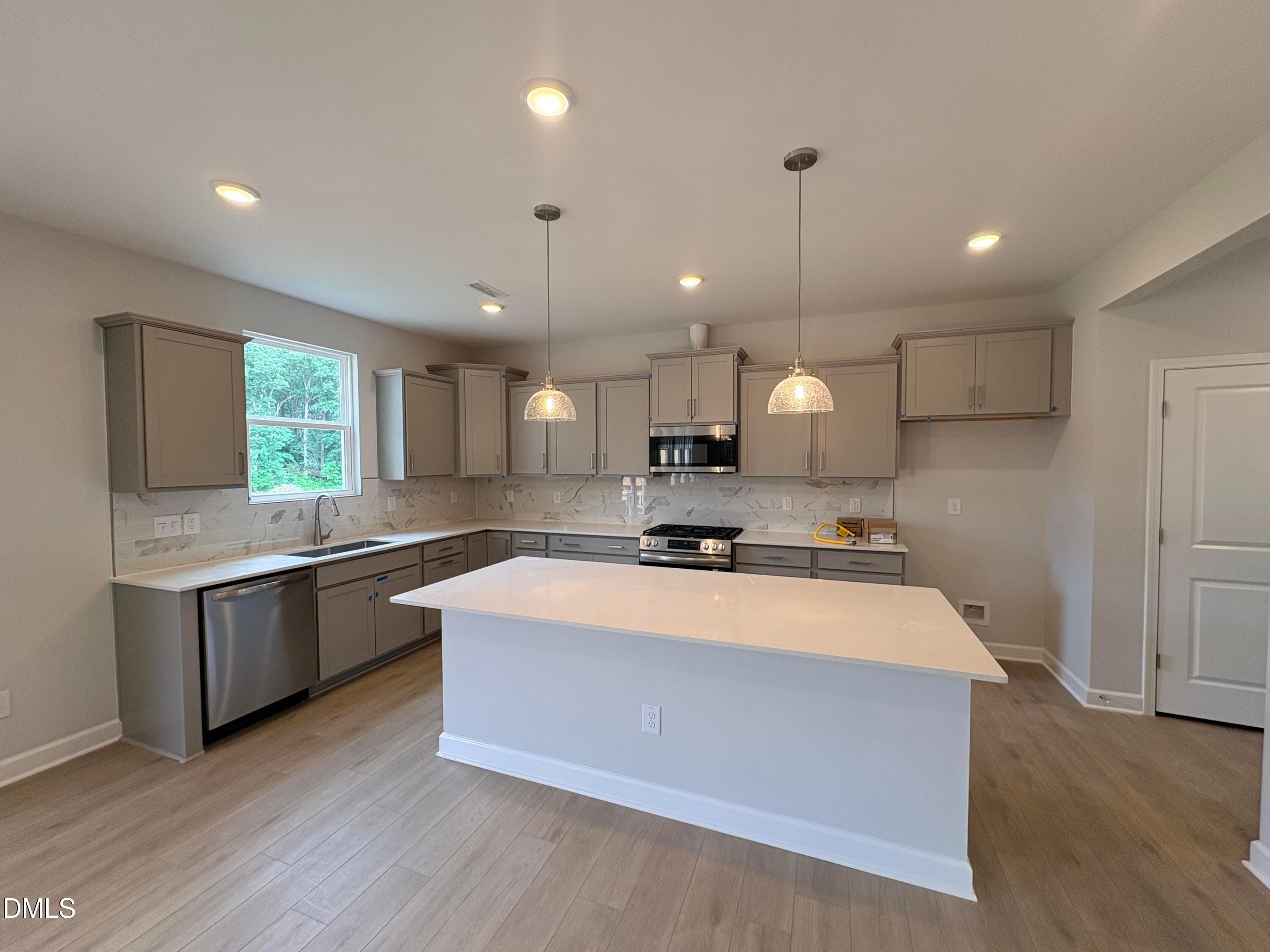 Modern kitchen with white island, gray cabinets, and stainless appliances in The Hickory II C home in Zebulon, NC.