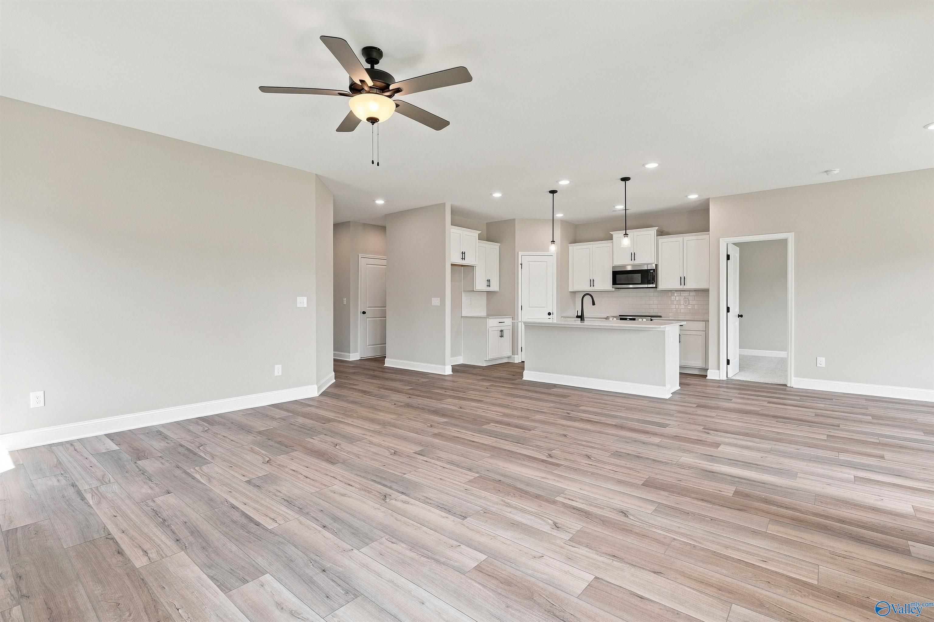 Open-concept living area with luxury vinyl plank flooring and white kitchen island in The Franklin C, Toney, Alabama