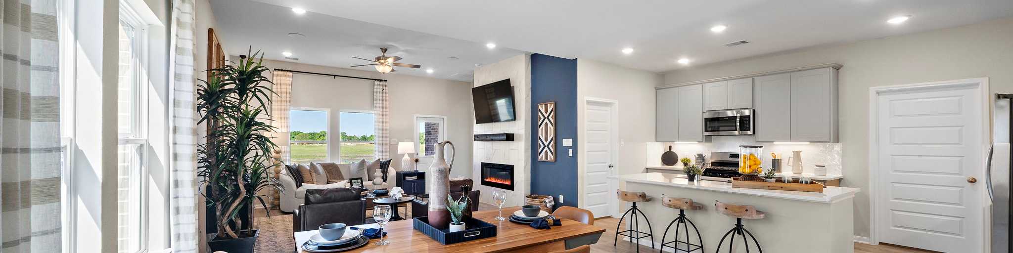 Open-concept kitchen and dining area in Emberly Beasley TX Davidson Homes with hardwood floors, large windows, and modern island