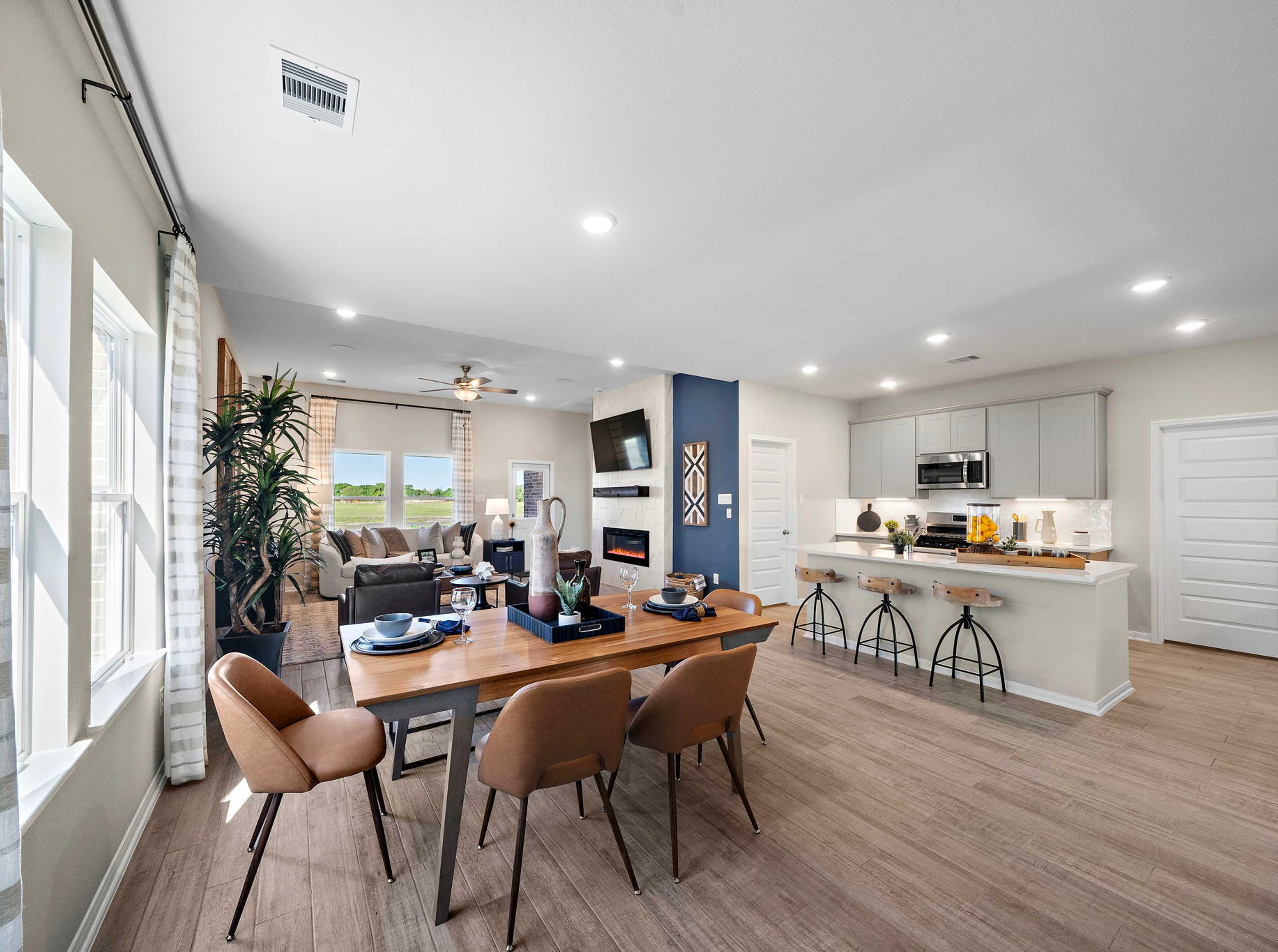 Open-concept kitchen and dining area in Emberly Beasley TX Davidson Homes with hardwood floors, large windows, and modern island