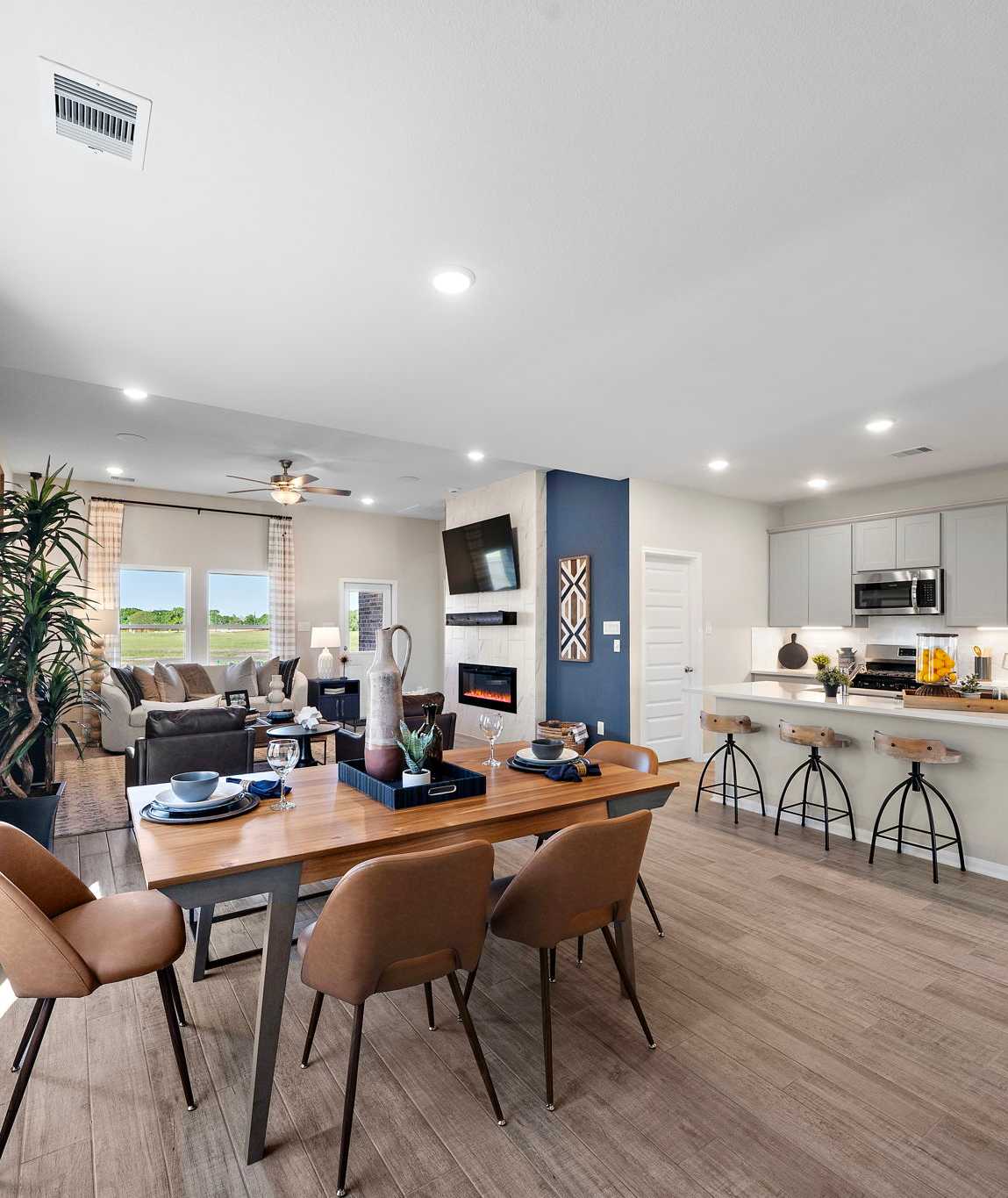 Open-concept kitchen and dining area in Emberly Beasley TX Davidson Homes with hardwood floors, large windows, and modern island