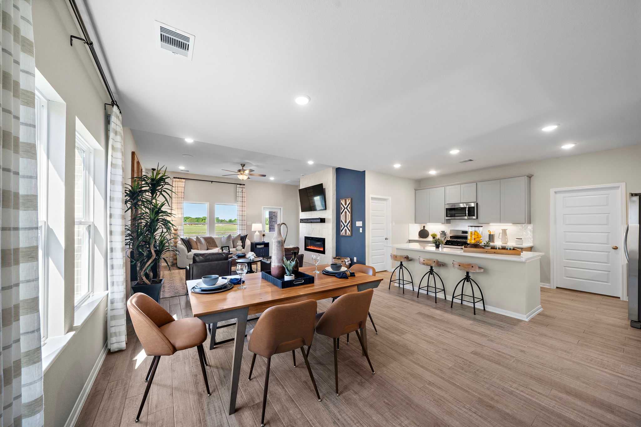 Open-concept kitchen and dining area in Emberly Beasley TX Davidson Homes with hardwood floors, large windows, and modern island