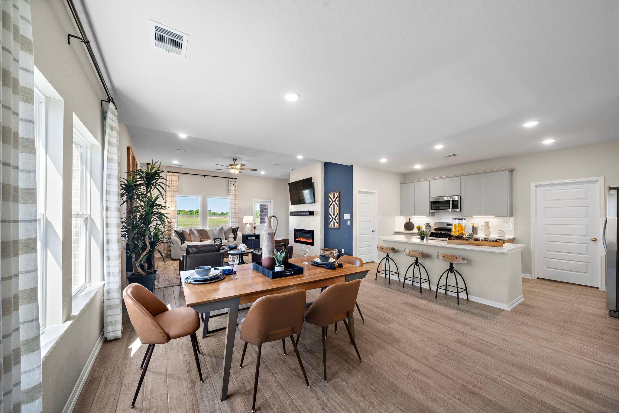 Open-concept kitchen and dining area in Emberly Beasley TX Davidson Homes with hardwood floors, large windows, and modern island
