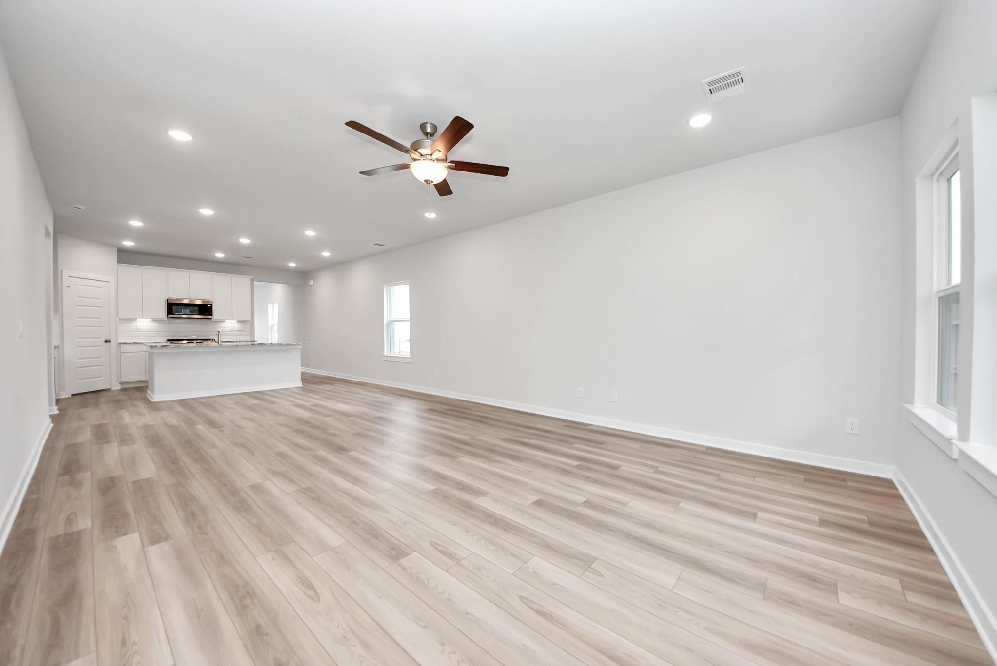 Spacious open-concept living area with wood-style flooring in Davidson Homes Sabine E floor plan, Windmill Estates, Magnolia.