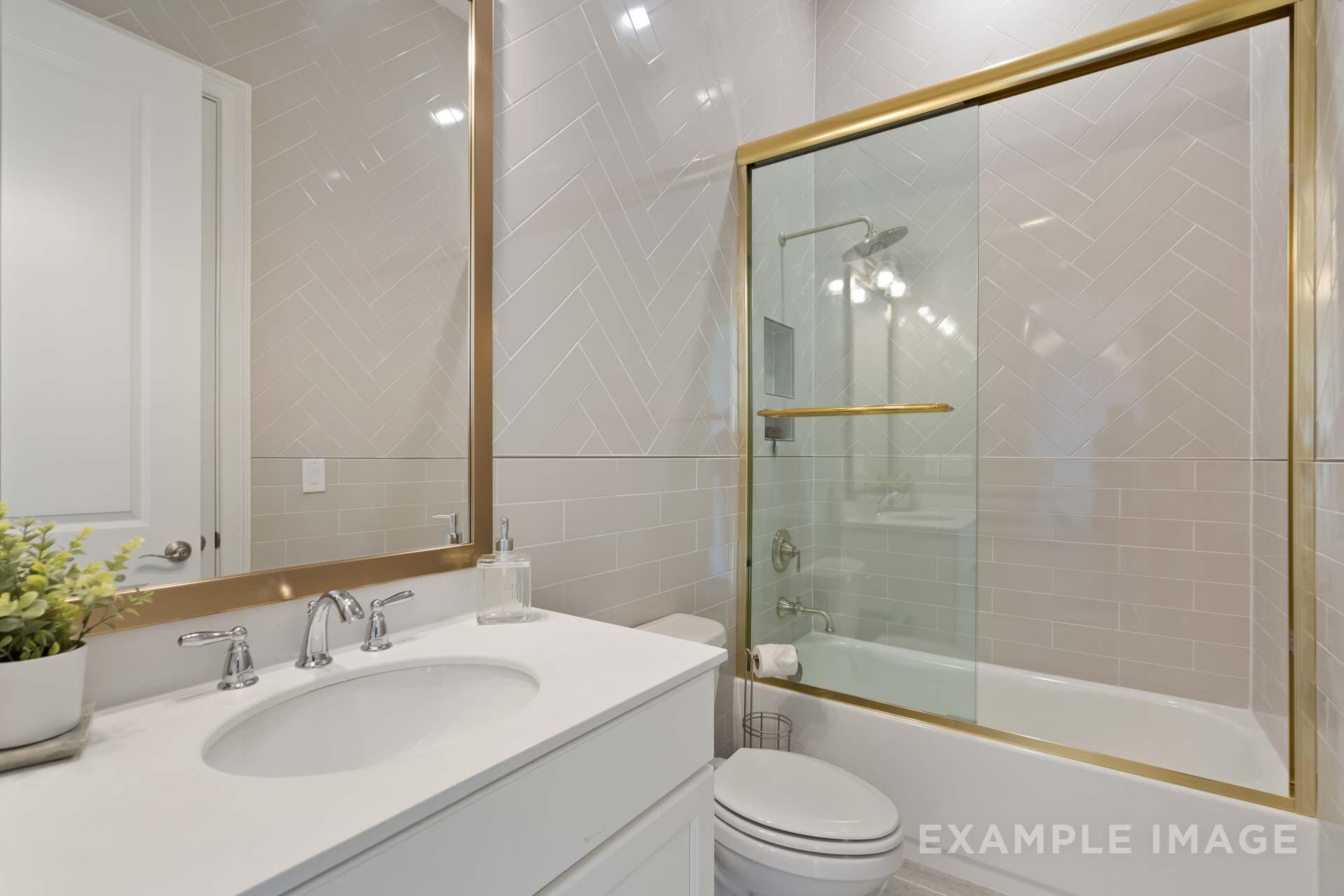 Luxury master bathroom in The Seaside C featuring gold-accented glass shower, soaking tub, and white vanity