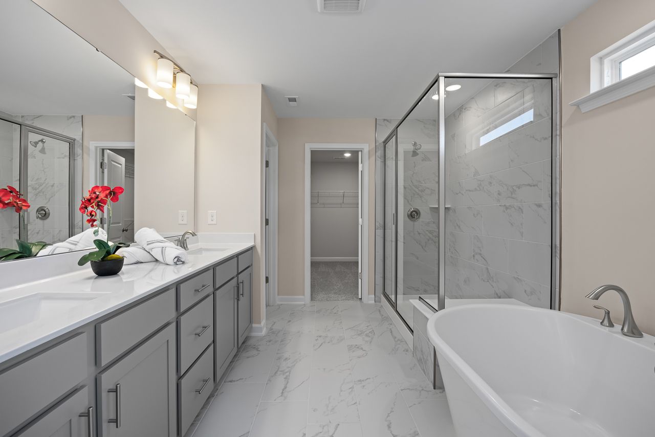Luxury master bathroom in The Chestnut featuring dual vanities, a glass-enclosed shower, and a soaking tub.