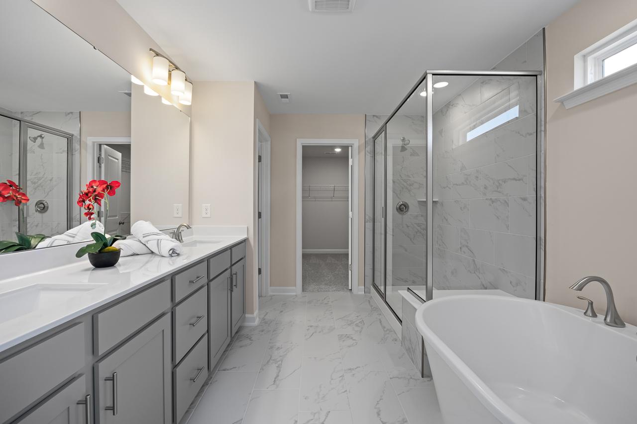 Luxury master bathroom in The Chestnut featuring dual vanities, a glass-enclosed shower, and a soaking tub.