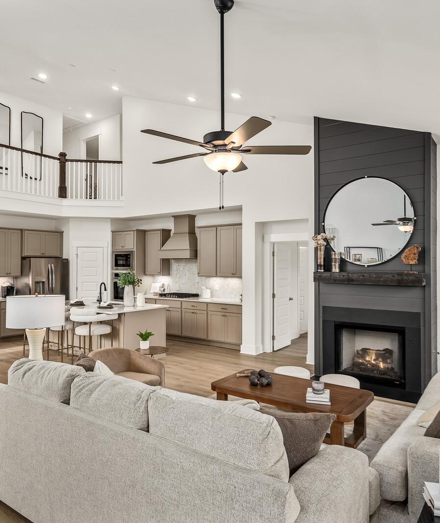 Spacious modern living room with white walls, open white kitchen, light gray sofa with green pillows, glass coffee table, har