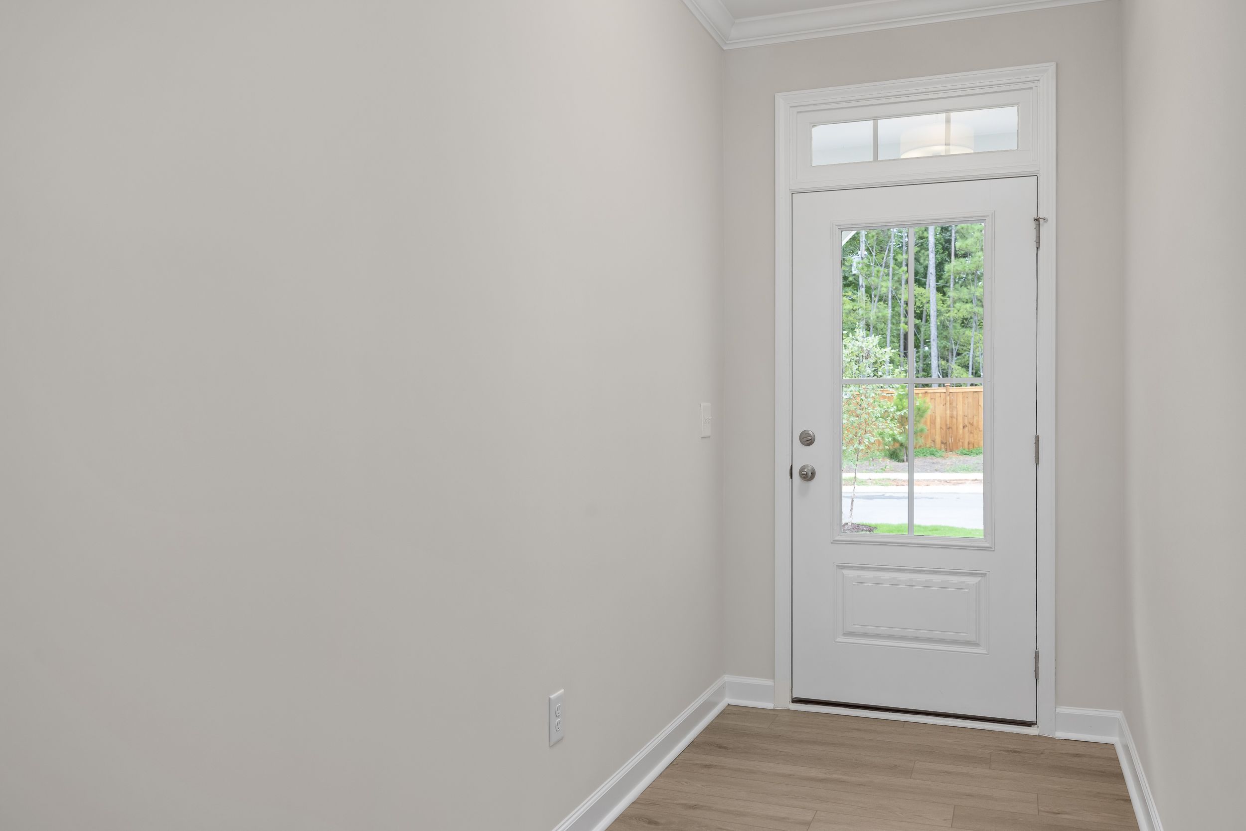 Interior hallway of The Beech 2-story home with white glass door overlooking fenced backyard greenery