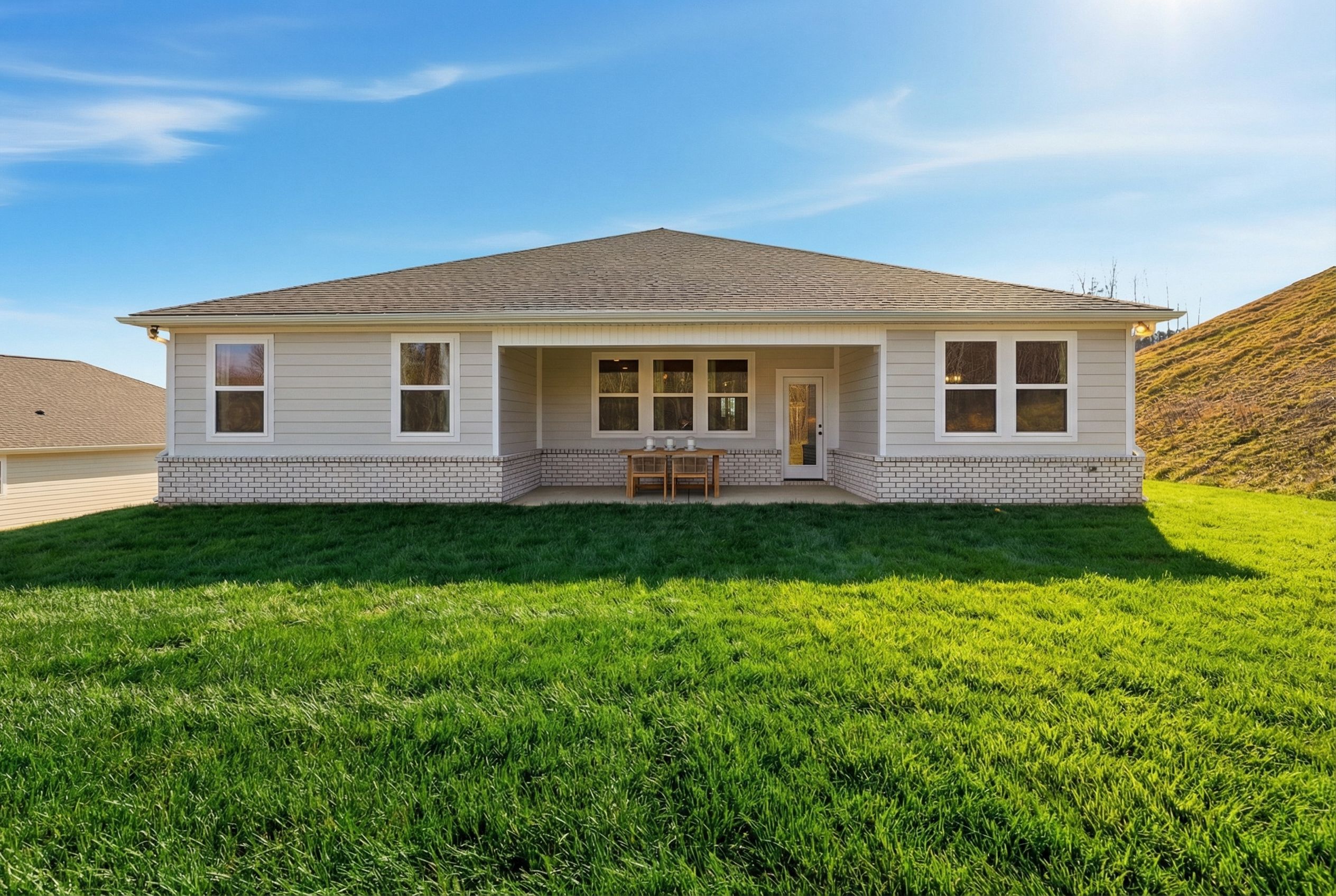 Rear elevation of The Hibiscus F 1-story home featuring covered patio, large windows, French doors, outdoor seating, and lush green lawn