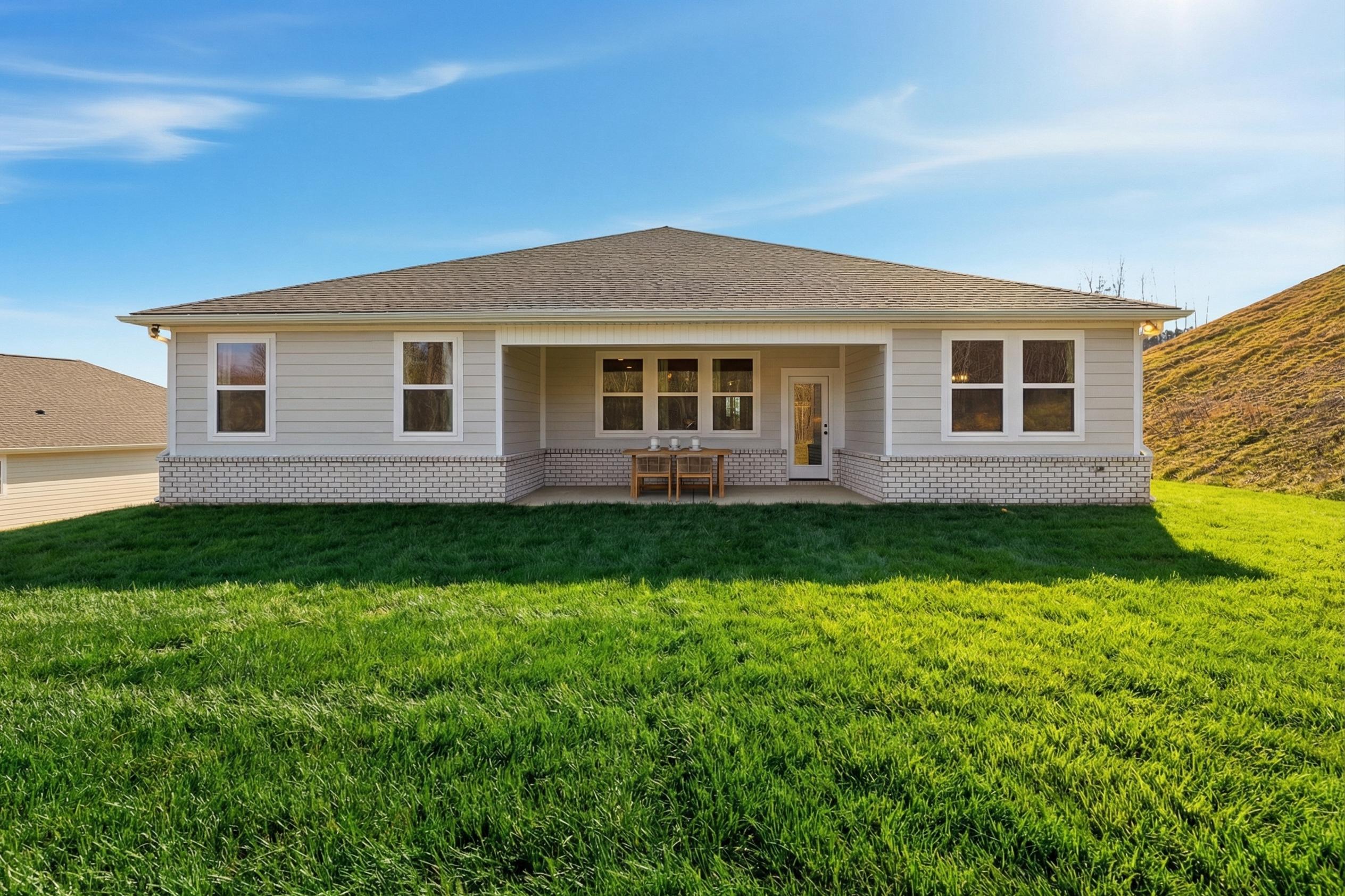 Rear elevation of The Hibiscus F 1-story home featuring covered patio, large windows, French doors, outdoor seating, and lush green lawn