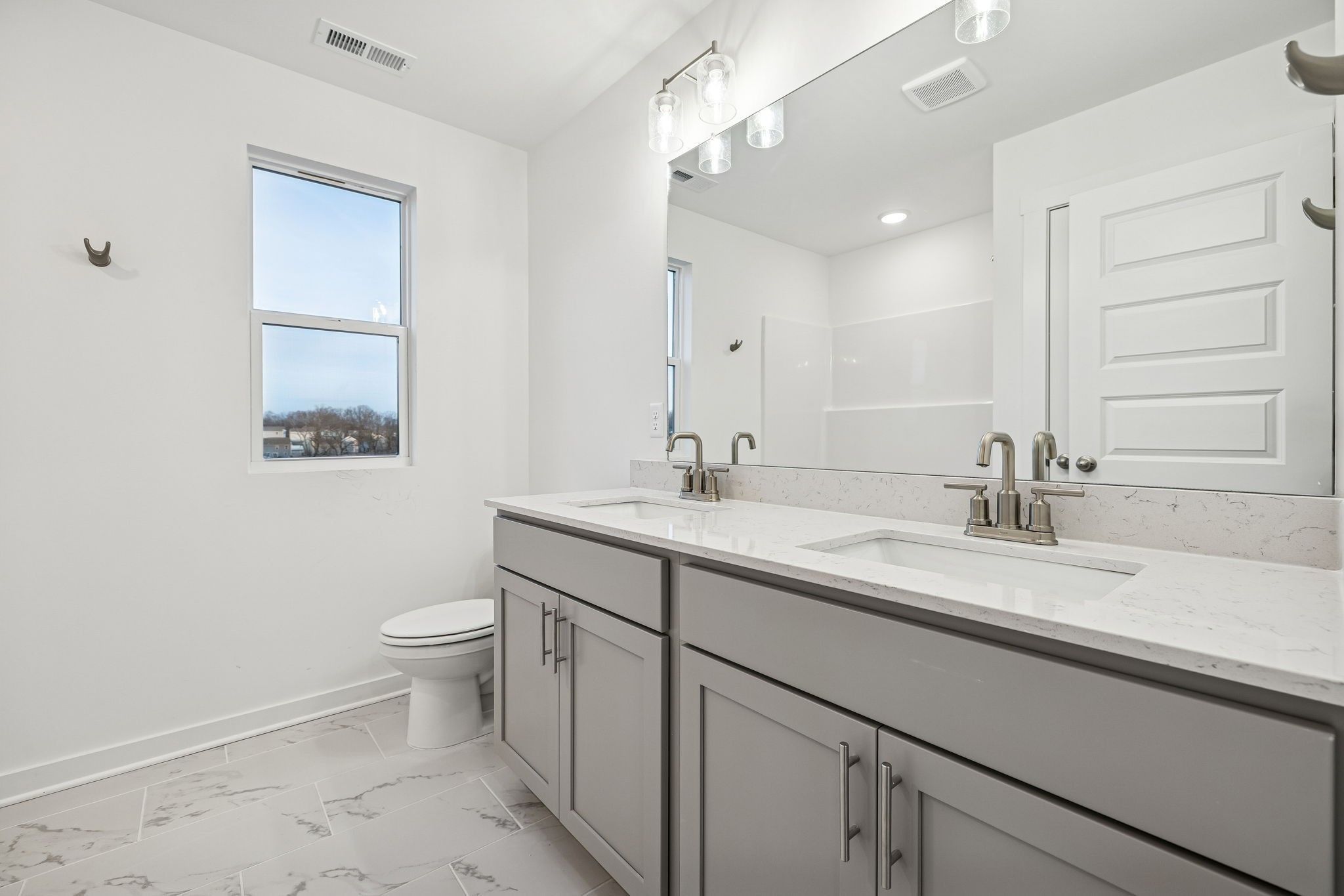 Modern double vanity bathroom with quartz counters, gray cabinets, and marble-look tile in Davidson Homes The Willow, Calista Farms, White House, TN