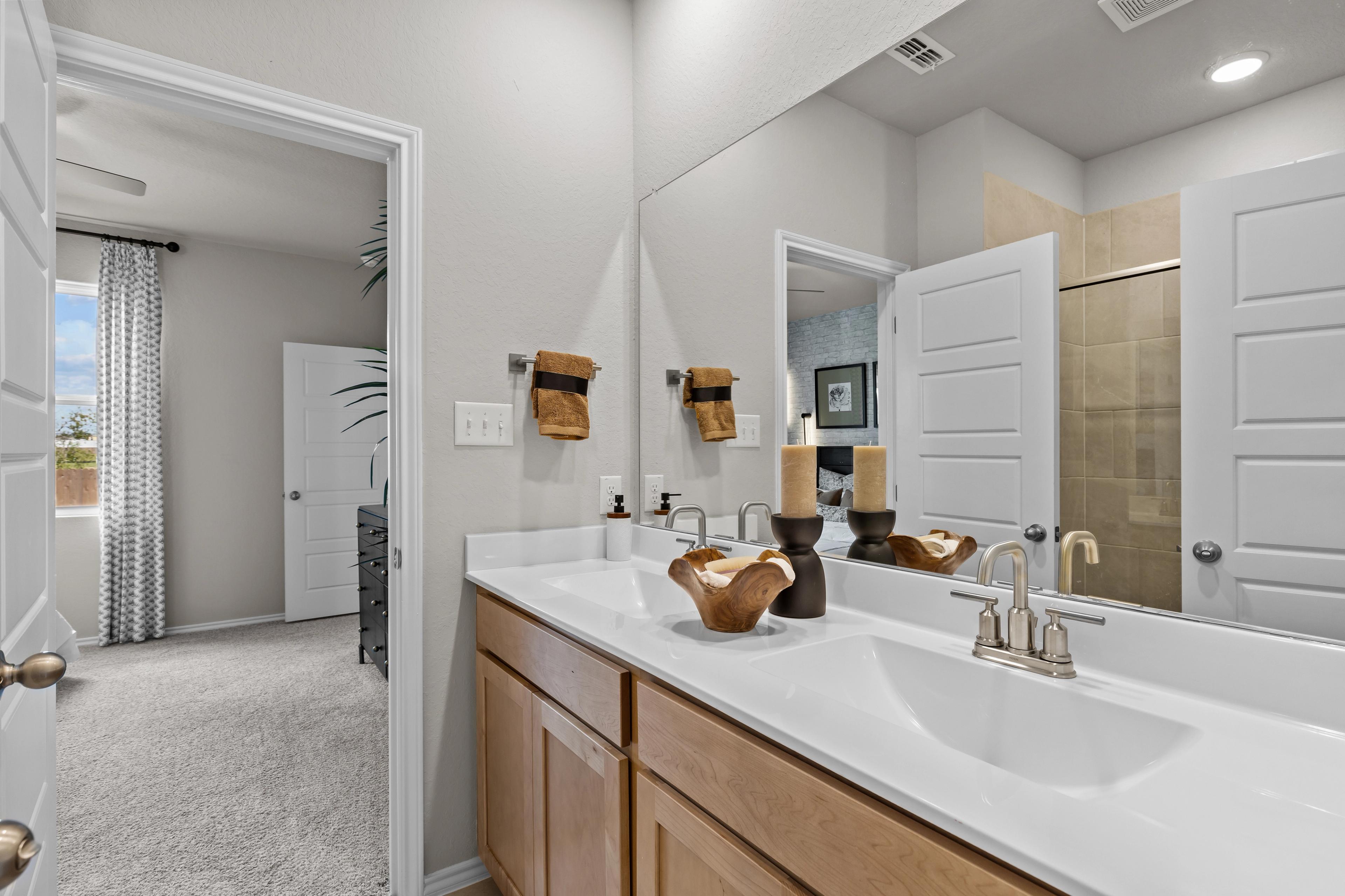 Spacious master bathroom in The Sabine by Davidson Homes featuring double oak vanity, large mirror, and neutral finishes