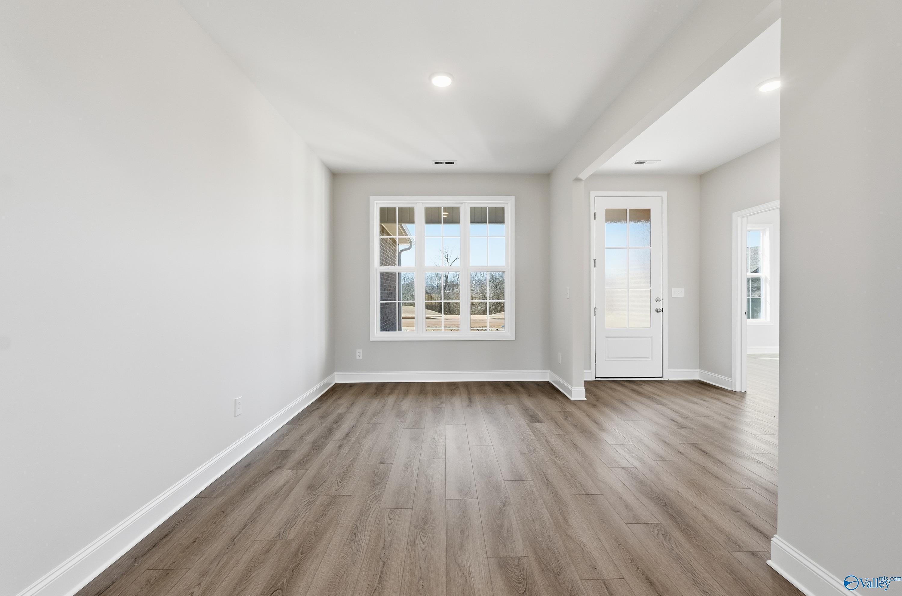 Bright entry foyer with hardwood floors, large windows, and glass door in Davidson Homes The Finleigh, Harvest, AL