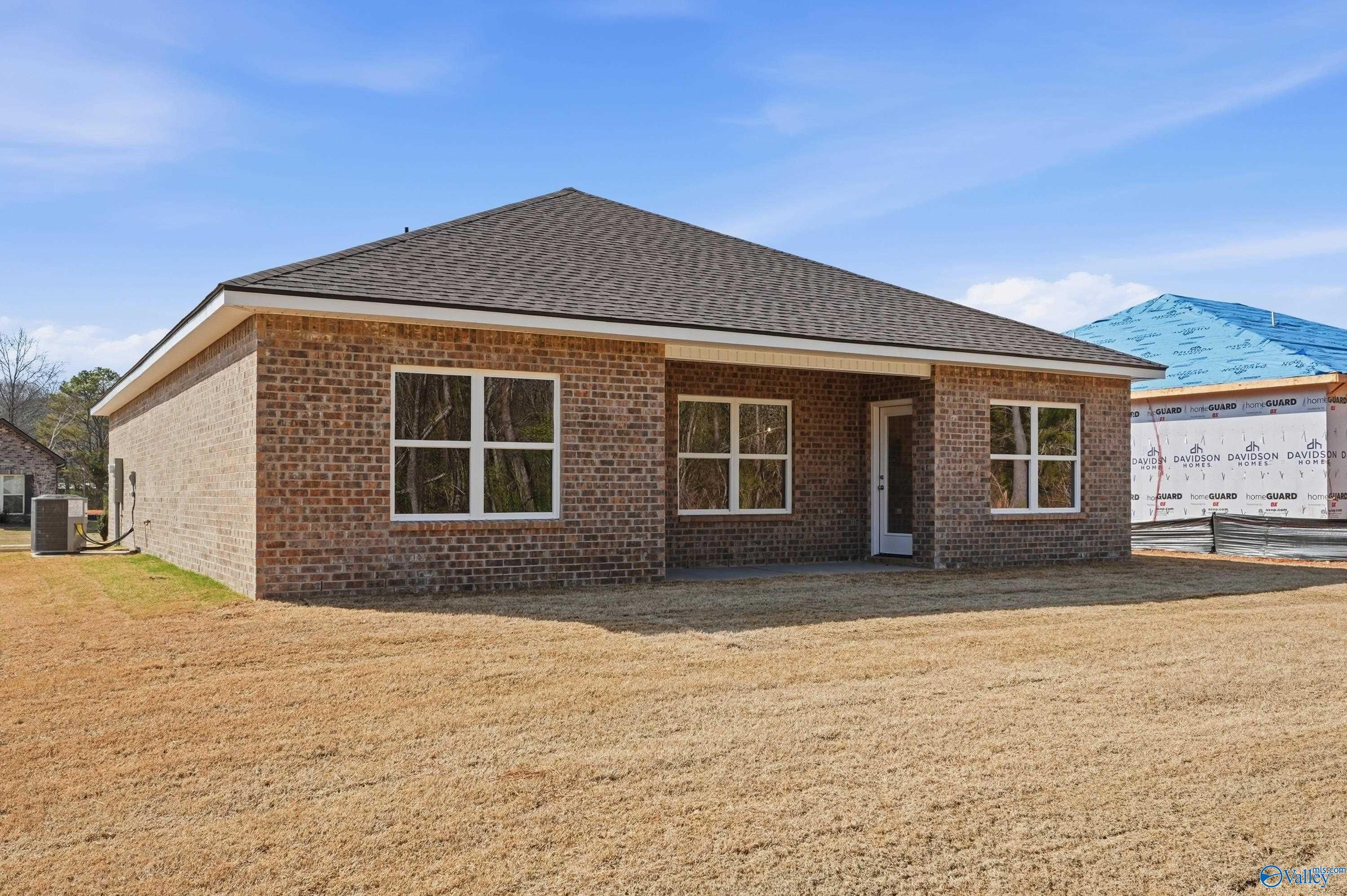 Brick single-story home exterior with red brick facade, dark shingle roof, large windows, and front entry in Spragins Cove, Huntsville, Alabama - The Asheville by Davidson Homes