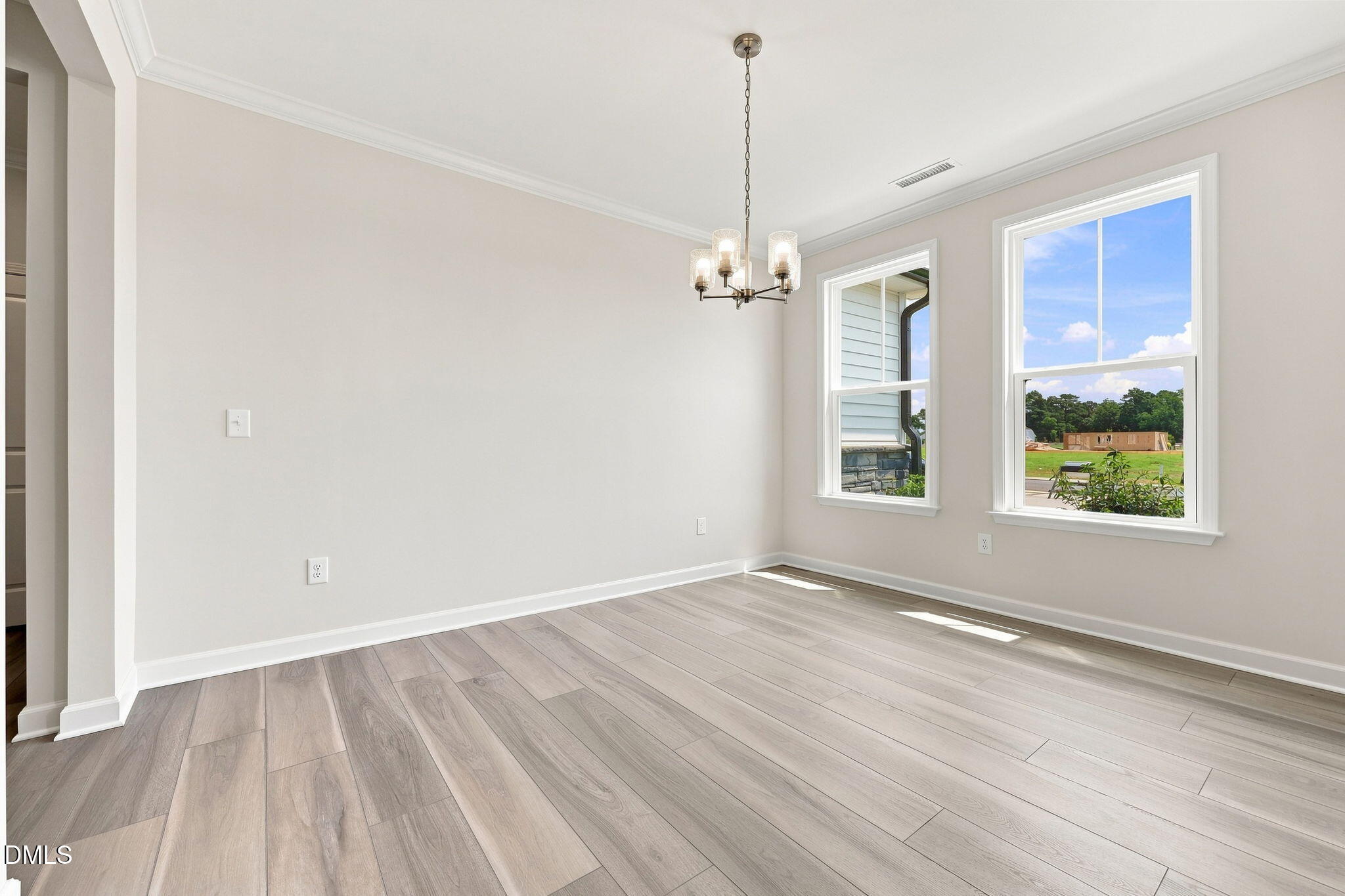 Bright dining room with modern chandelier and wood-look floors in The Magnolia B at Retreat at North Main, Lillington, NC.