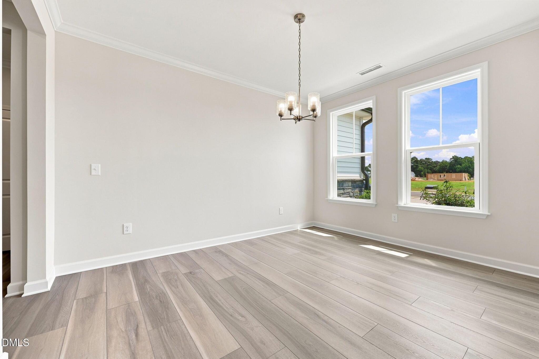 Bright dining room with modern chandelier and wood-look floors in The Magnolia B at Retreat at North Main, Lillington, NC.