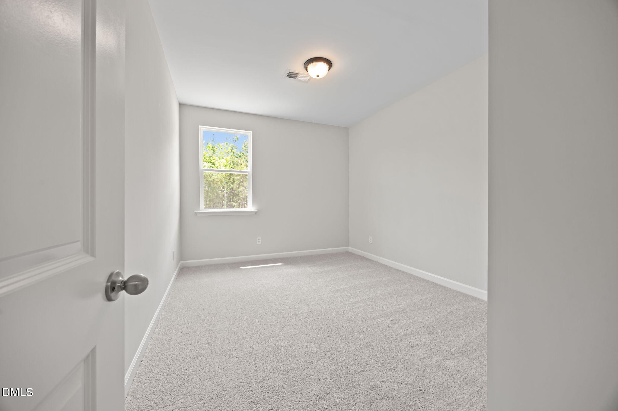 Empty bedroom with light gray walls, beige carpet, large window with greenery view in Davidson Homes The Willow D, Wendell, NC