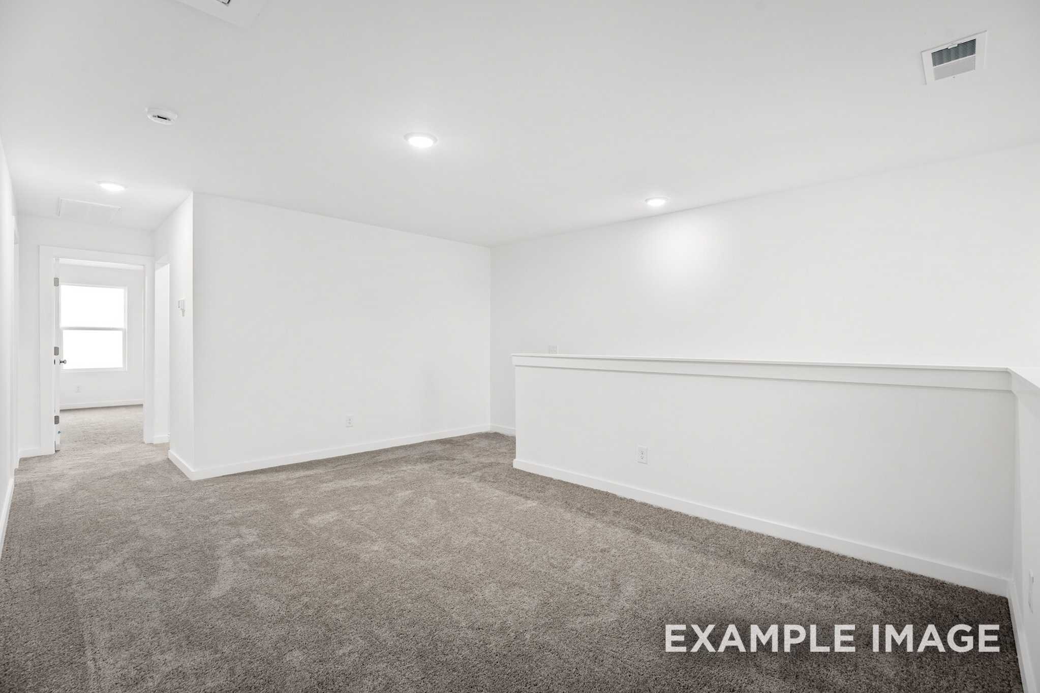 Spacious upstairs hallway in The Grayson C with gray carpet, white walls, recessed lights, and balcony railing by Davidson Homes