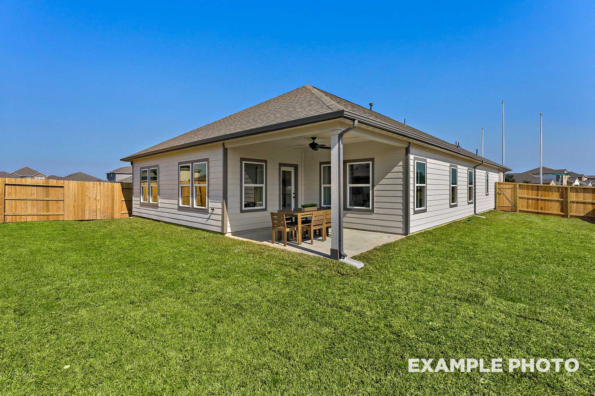 Corner view of The Everett E single-story home with covered patio, ceiling fan, and lush green lawn in Crosby, Texas