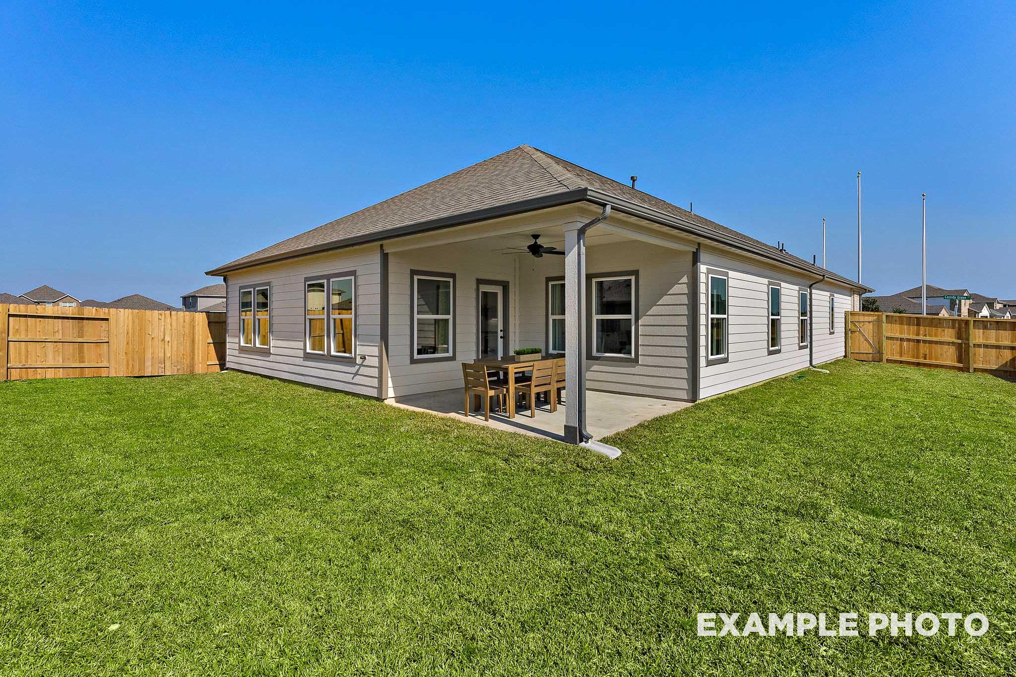 Corner view of The Everett E single-story home with covered patio, ceiling fan, and lush green lawn in Crosby, Texas