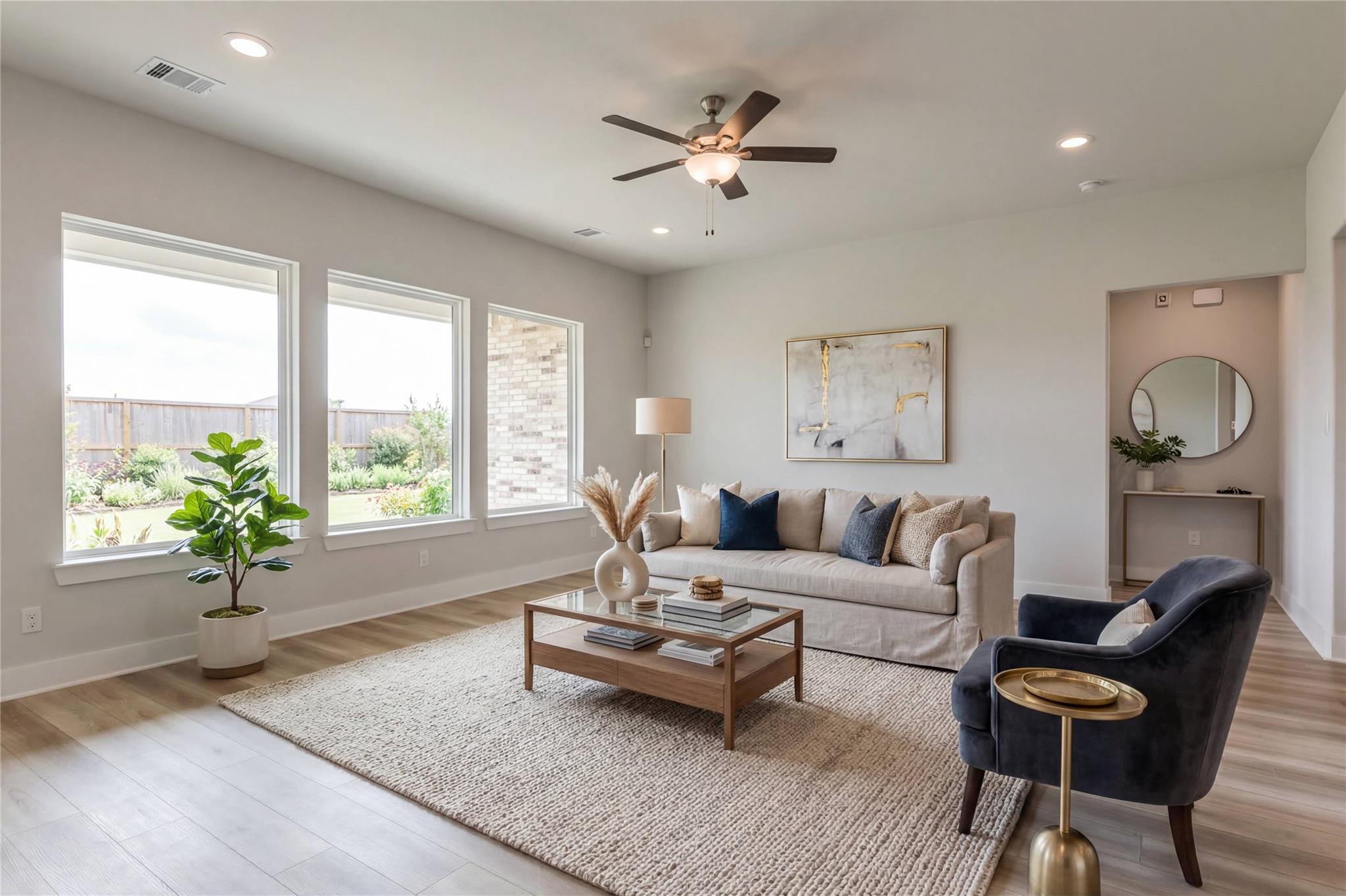 Cozy living room with large windows, neutral sofa, fiddle leaf plant, abstract art in Davidson Homes The Edward A, Lago Mar, Texas City
