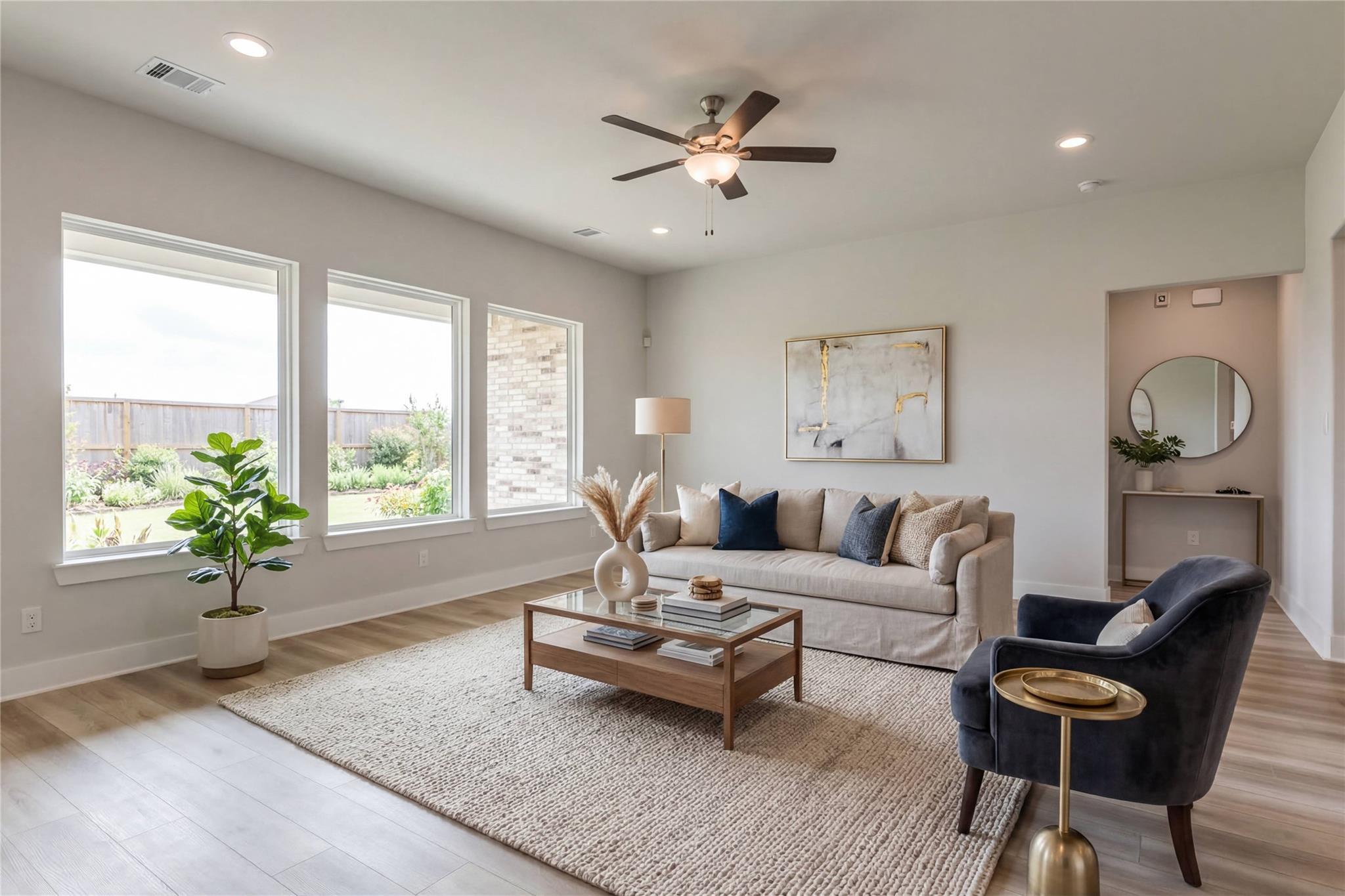 Cozy living room with large windows, neutral sofa, fiddle leaf plant, abstract art in Davidson Homes The Edward A, Lago Mar, Texas City