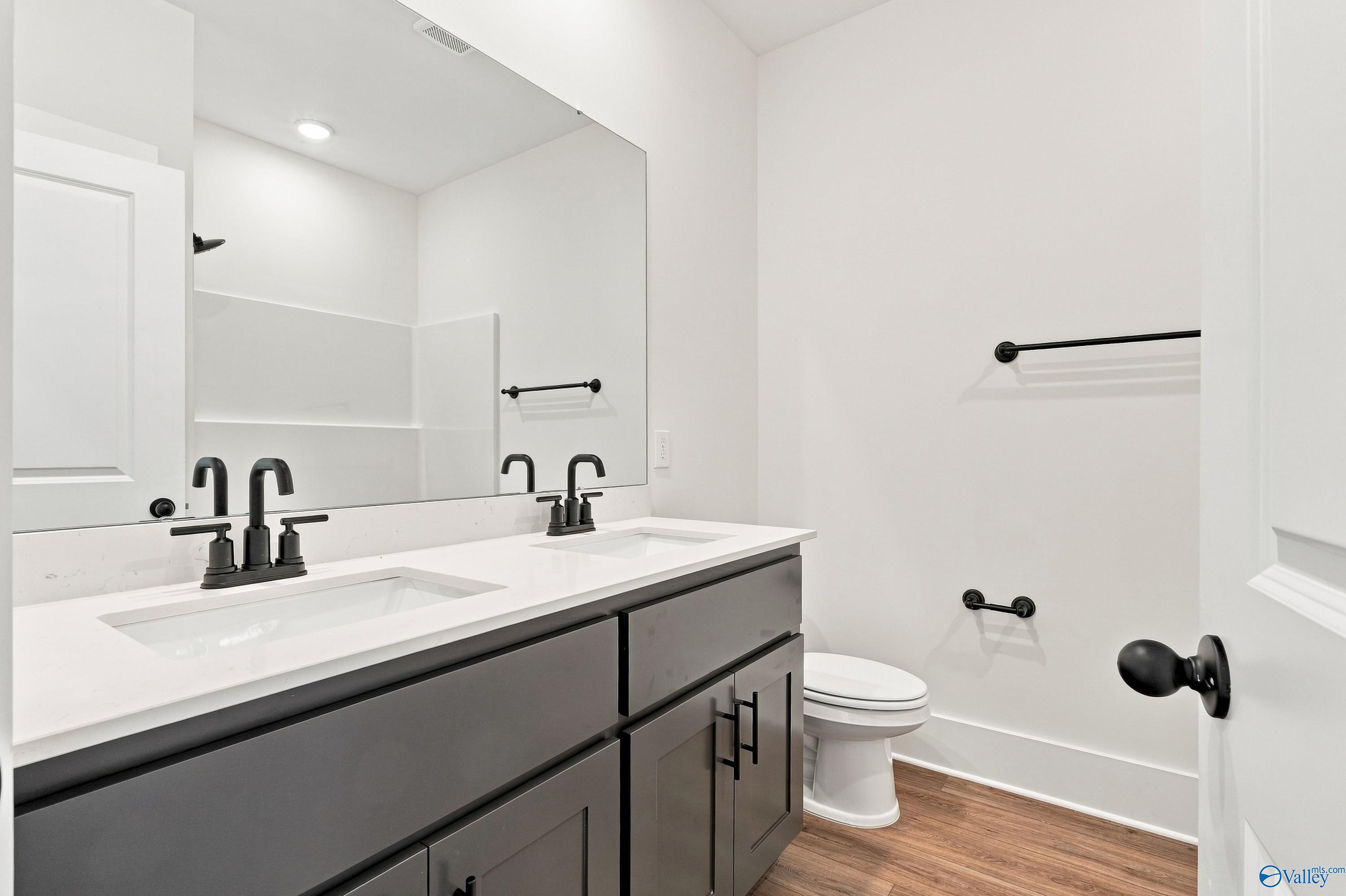 Dual vanity bathroom with dark gray cabinets, matte black faucets, and white quartz countertops in The Valencia, Huntsville, Alabama