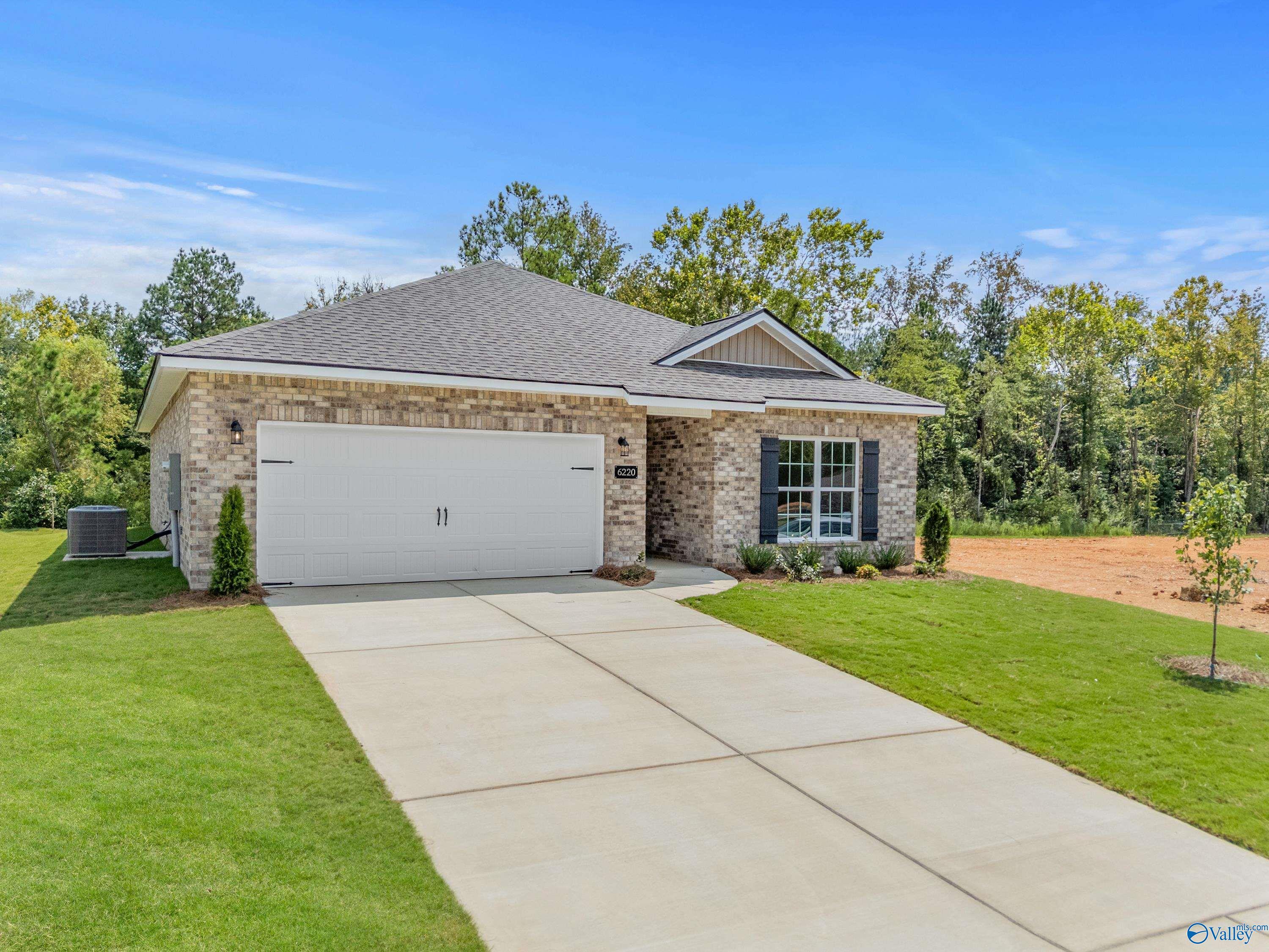 Modern brick single-story home with 2-car garage, concrete driveway, and landscaped yard in Spragins Cove, Huntsville, Alabama